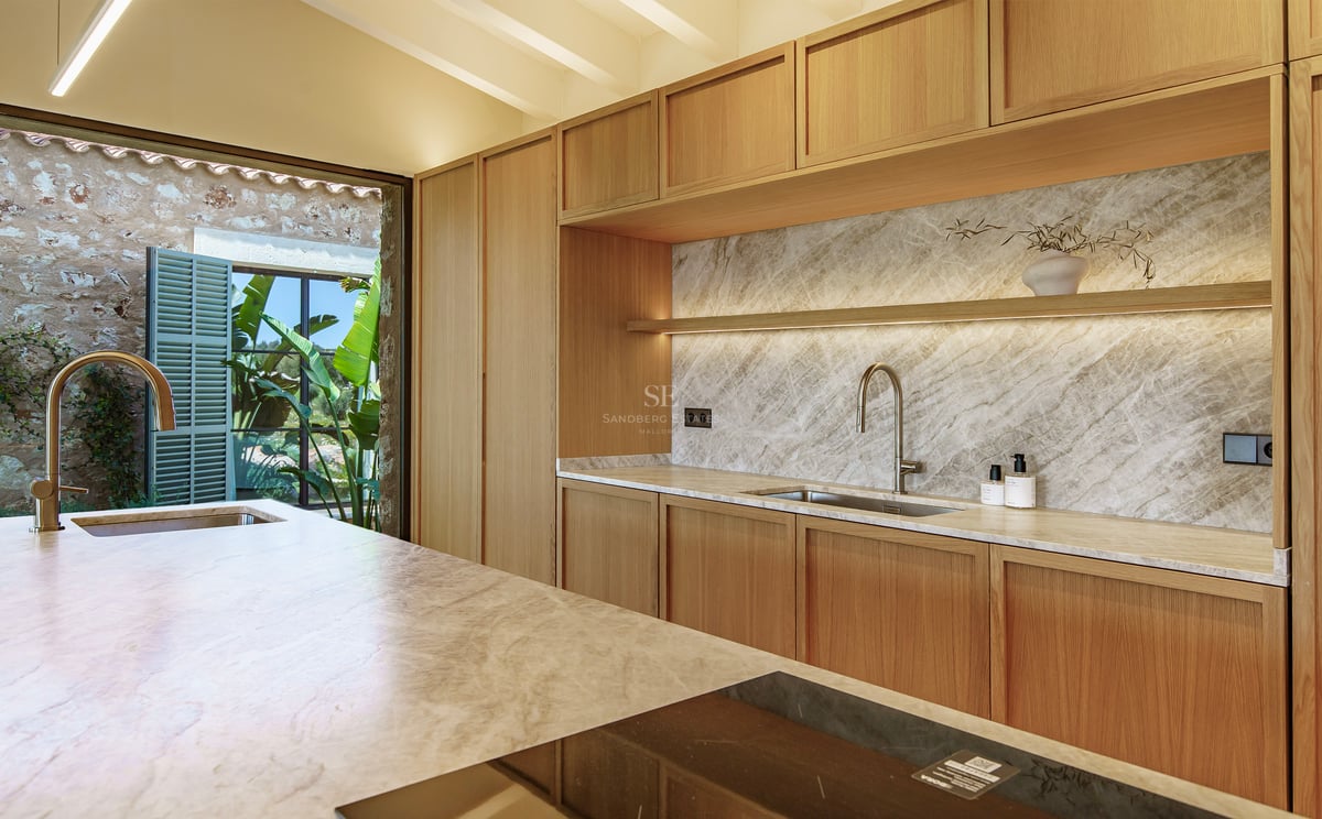 Moderne Küche mit hellen Holzschränken, Marmorrückwand und Kochinsel mit Induktionskochfeld.