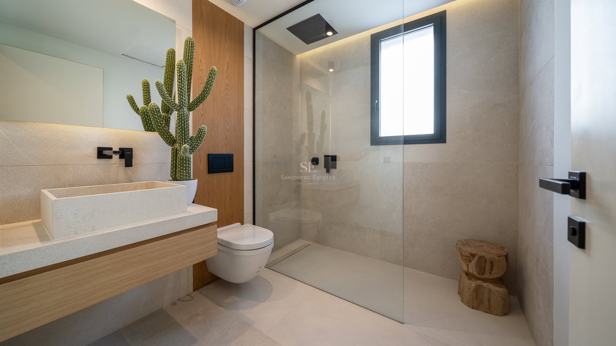 Salle de bains moderne avec douche à l'italienne, vasque en pierre et robinetterie noire mate.