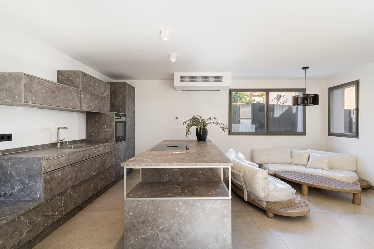 Modernt kök med grå marmorliknande skåp, köksö och integrerade vitvaror.