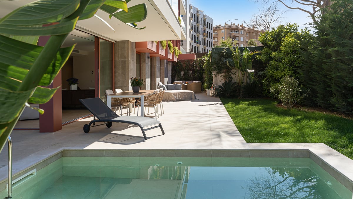 Luxury outdoor terrace featuring a private plunge pool, dining area, and manicured lawn surrounded by greenery.