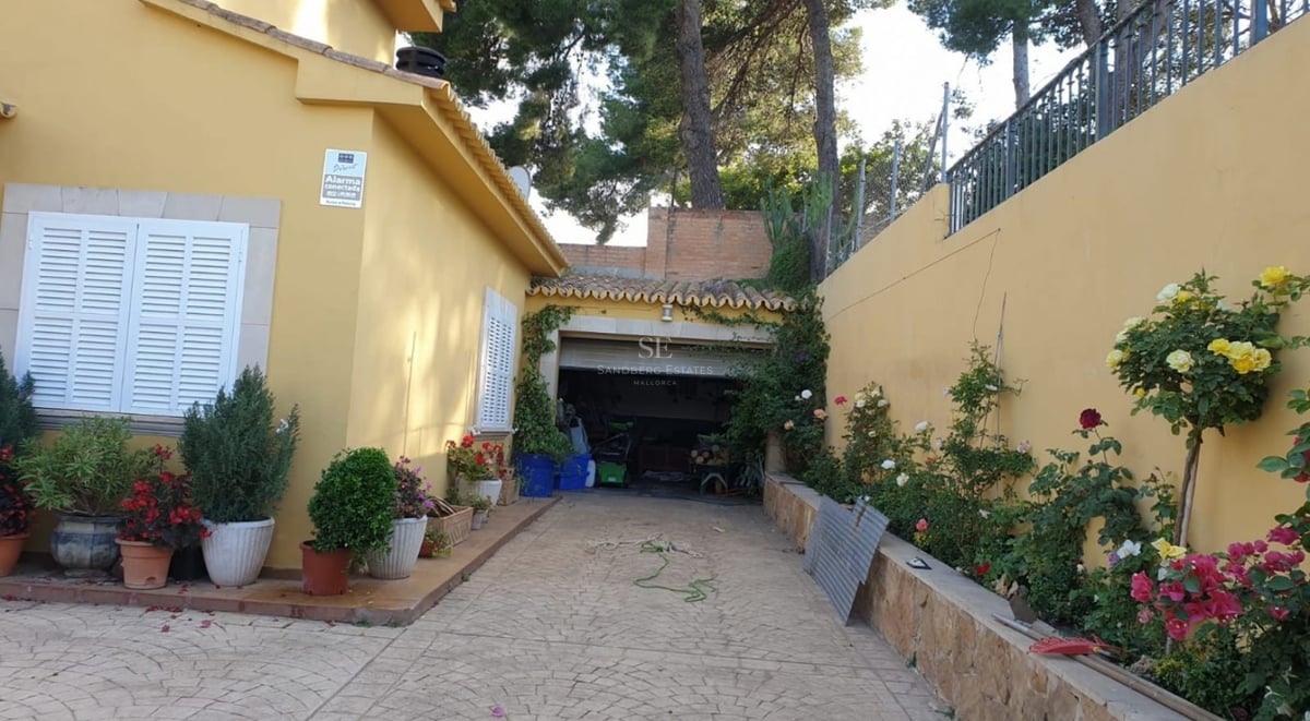 Aerial view of a luxurious villa with infinity pool, lush gardens, and modern architecture. Open spaces and large window fronts.
