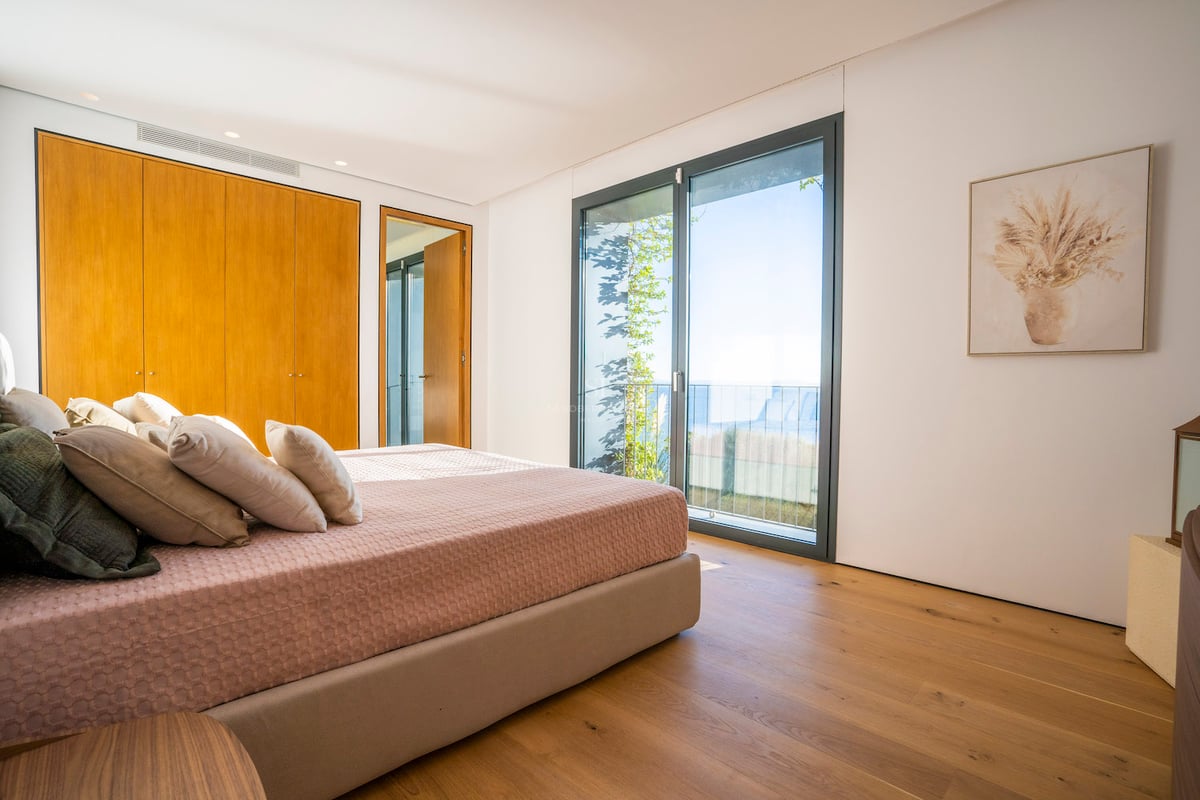 Schlafzimmer mit Eichenparkett, maßgefertigten Kleiderschränken und Schiebetüren mit Blick auf das Mittelmeer.