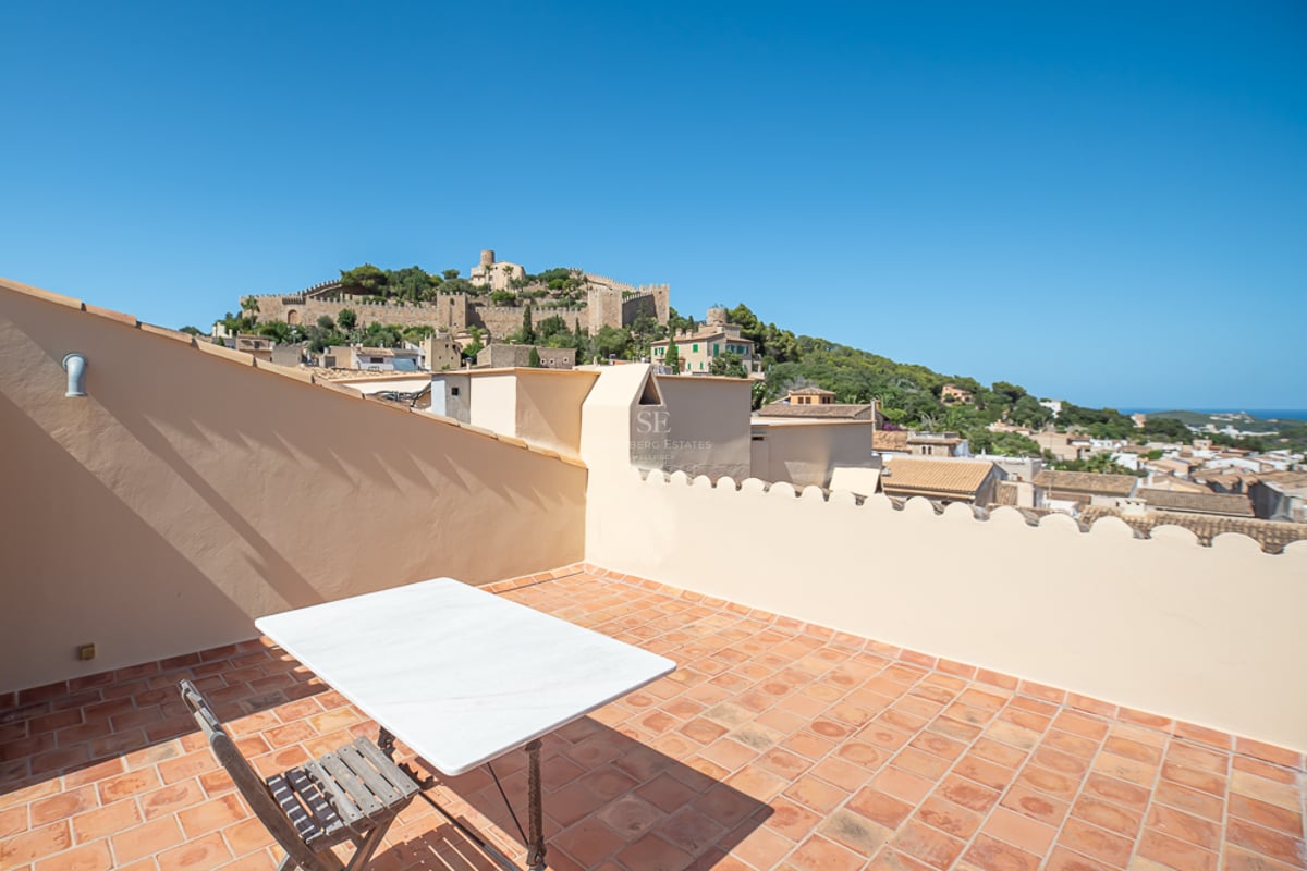 Terrasse sur le toit avec carrelage en terre cuite surplombant un château historique sur une colline verdoyante.