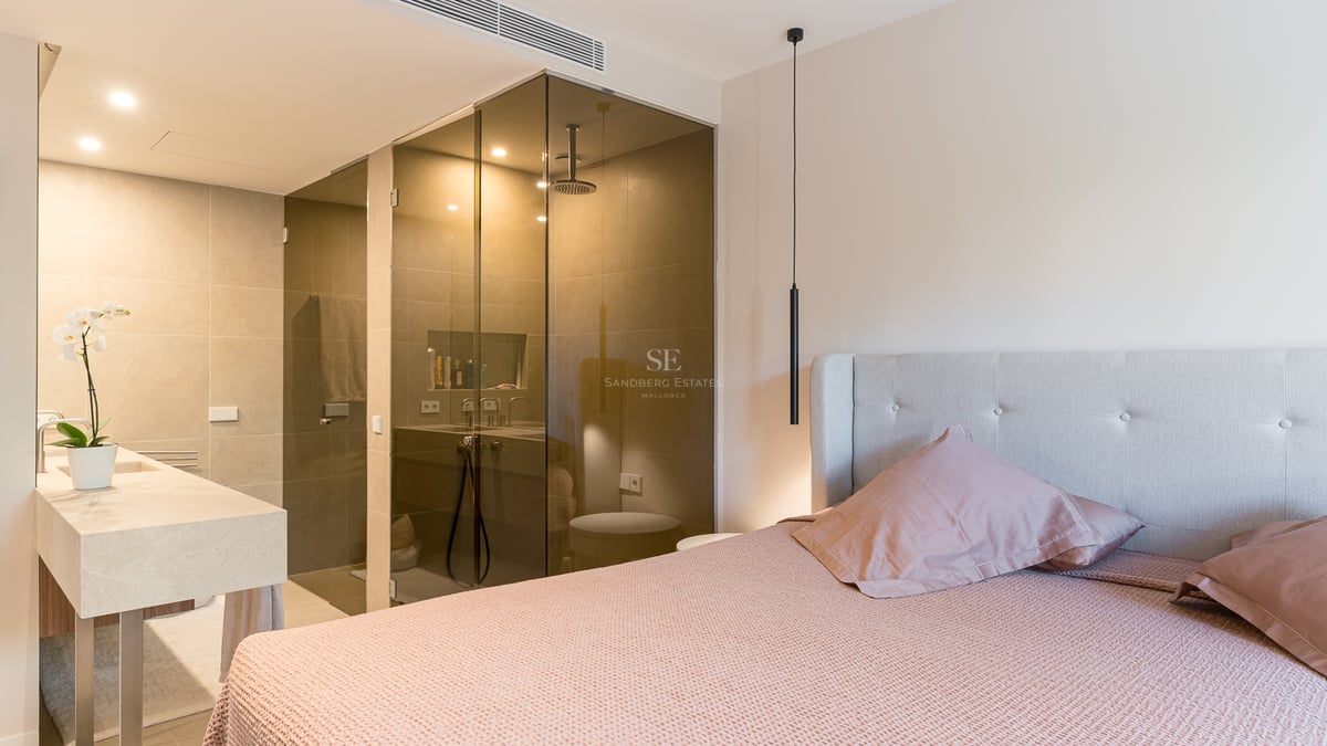 Contemporary master bedroom featuring a glass-enclosed shower, stone vanity, and dusty pink bedding.