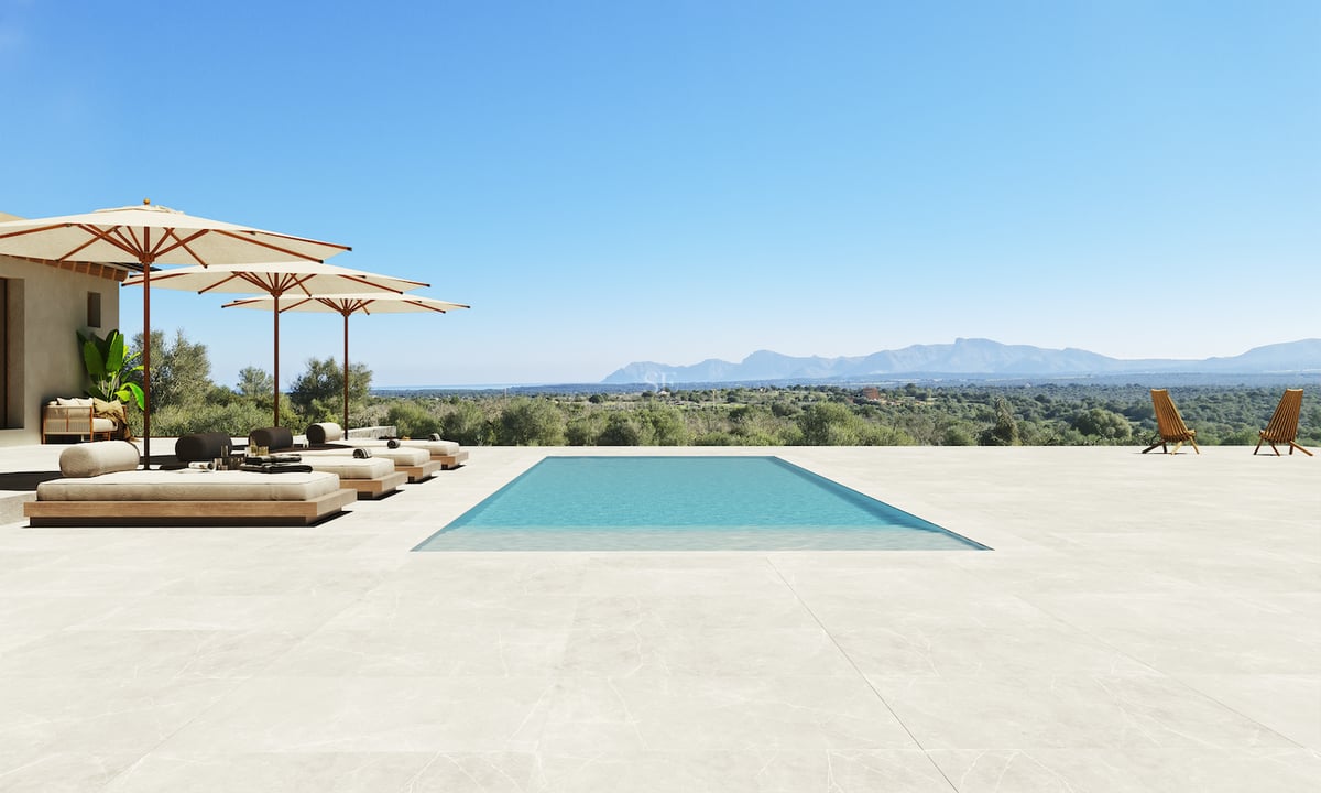 Piscine rectangulaire sur une vaste terrasse en pierre dominant un paysage montagneux sous un ciel bleu pur.
