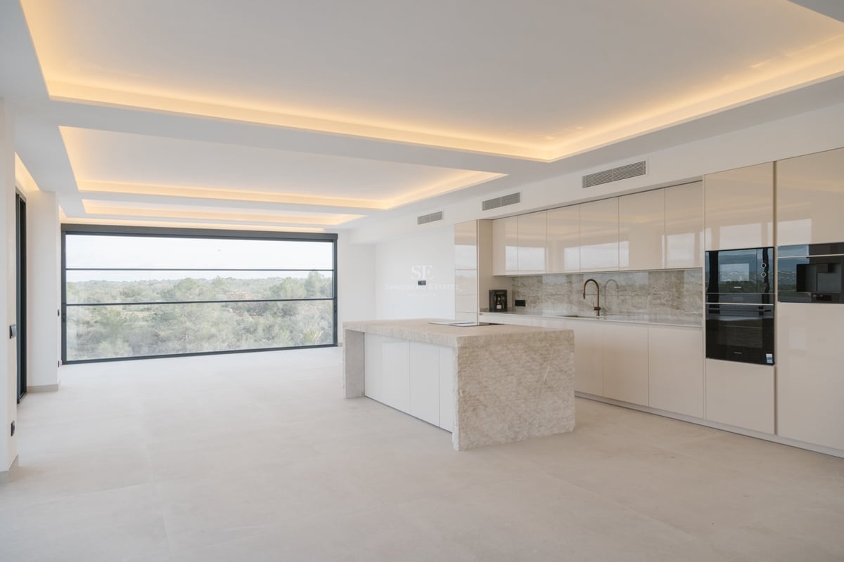 Moderne Küche mit Natursteininsel, Hochglanzschränken und bodentiefem Panoramafenster mit Blick ins Grüne.