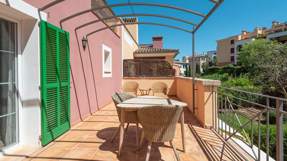 Private terrace with terracotta tiles, wicker furniture, and a metal pergola overlooking lush greenery.