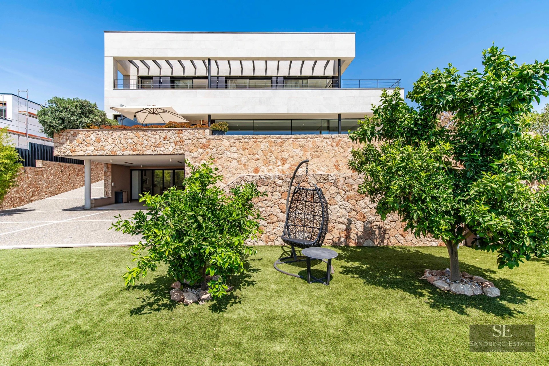 Exterior view of a modern house with a pool, sun loungers, and lush garden. Minimalist architecture with large windows.