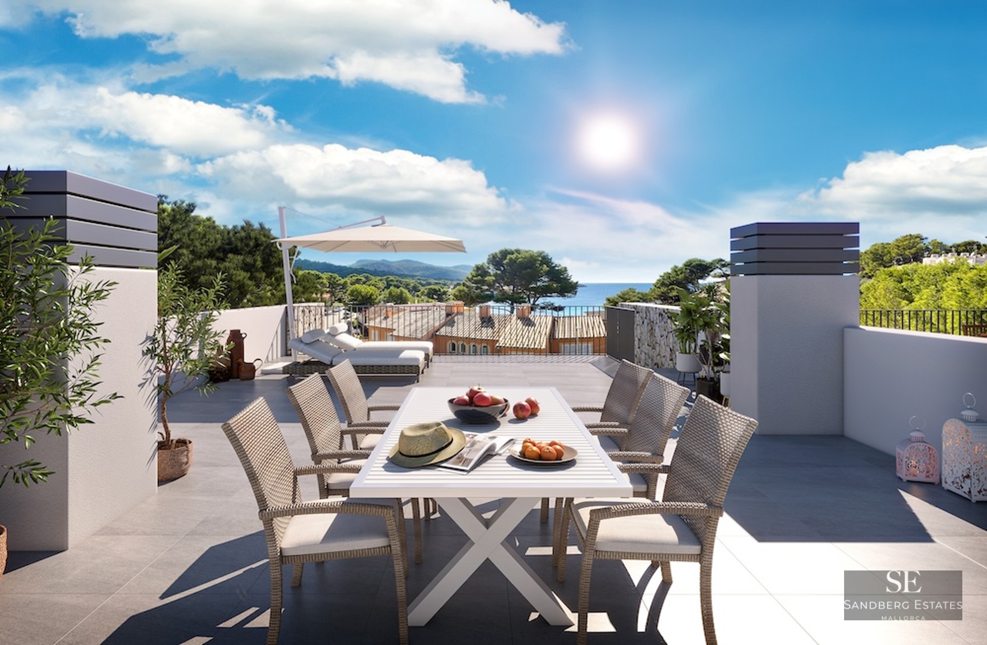 Sun-drenched rooftop terrace with white dining set, lounge chairs, and a panoramic view of the sea and coastal hills.