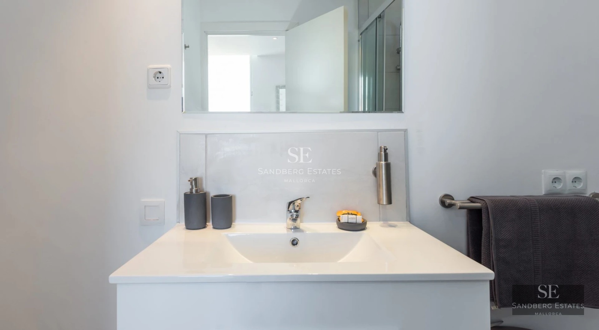 Spacious living room with floor-to-ceiling windows, wood floors, fireplace, and modern designer furniture. Pendant lights provide warm light.