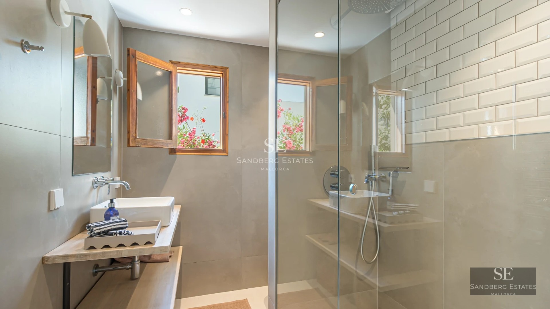 Spacious balcony with wood flooring, glass railing, and panoramic sea views. Modern and elegant furniture. Decorative plants.