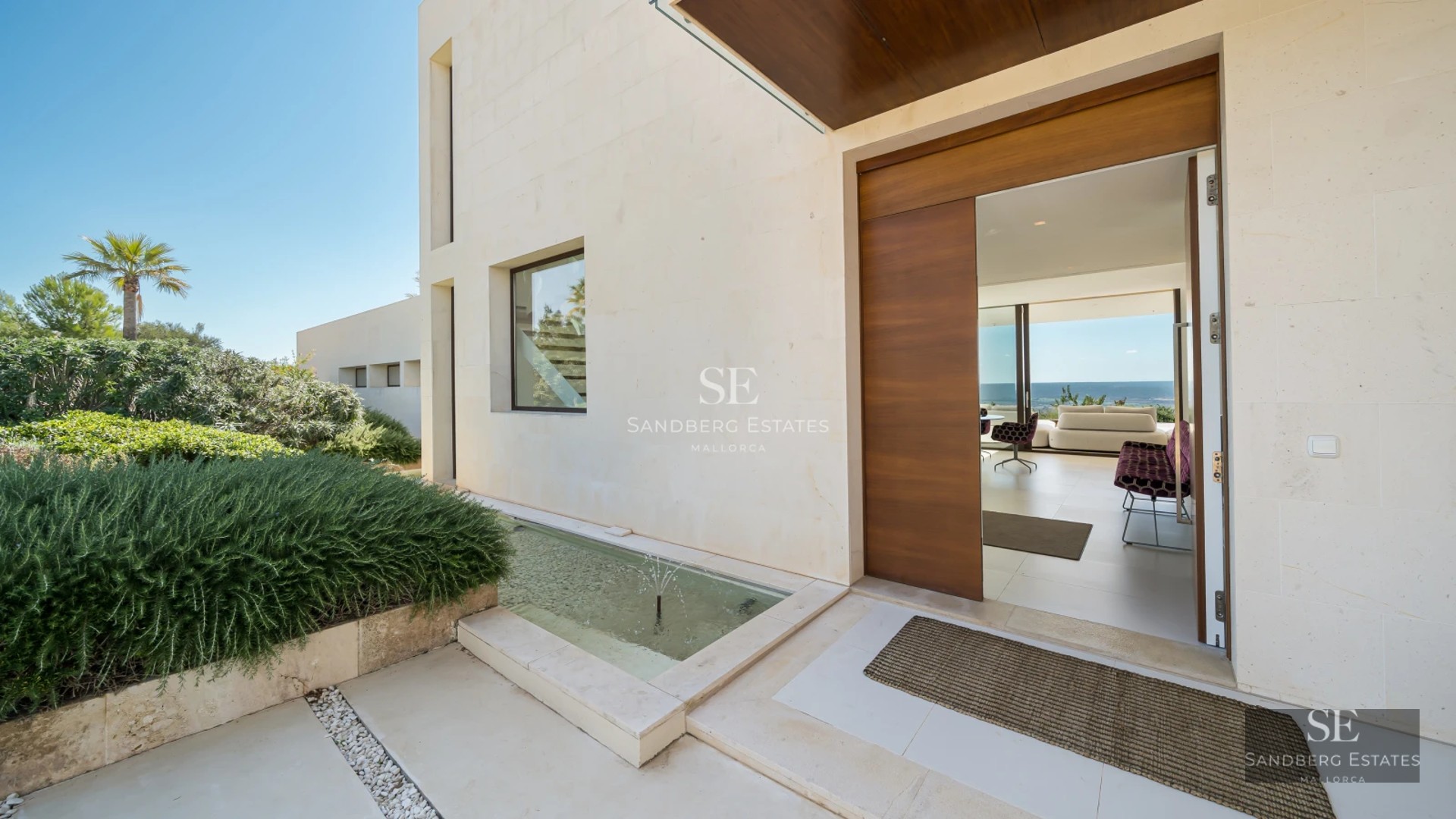 Exterior view of a modern house with a pool, large windows, wooden terrace, and lush vegetation. Minimalist architecture.