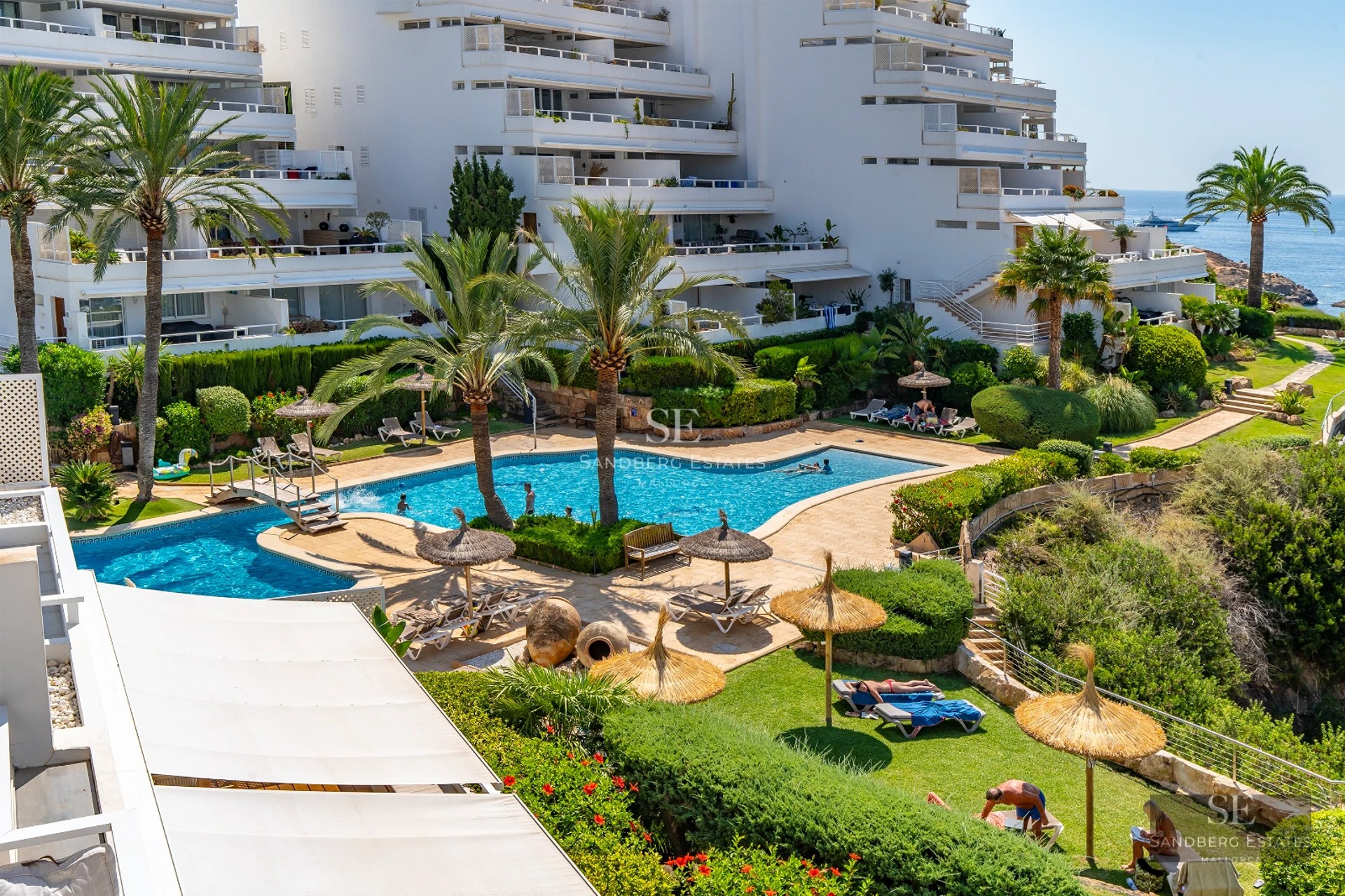 Exterior view of a modern villa featuring an infinity pool, terrace, and large windows offering panoramic sea views.