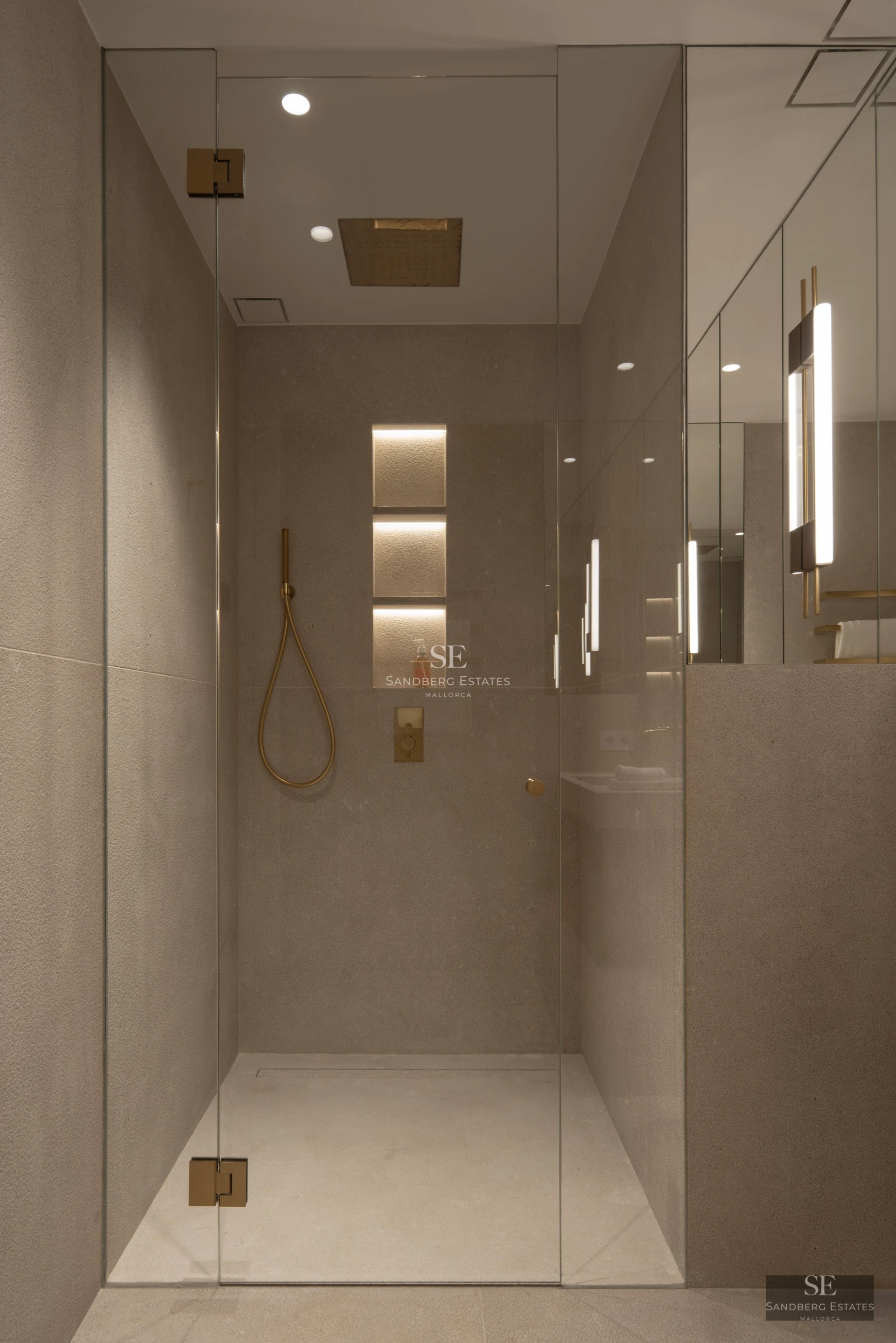 Spacious living room with floor-to-ceiling windows, natural light, light wood floors, and modern furniture in neutral tones. Garden view.