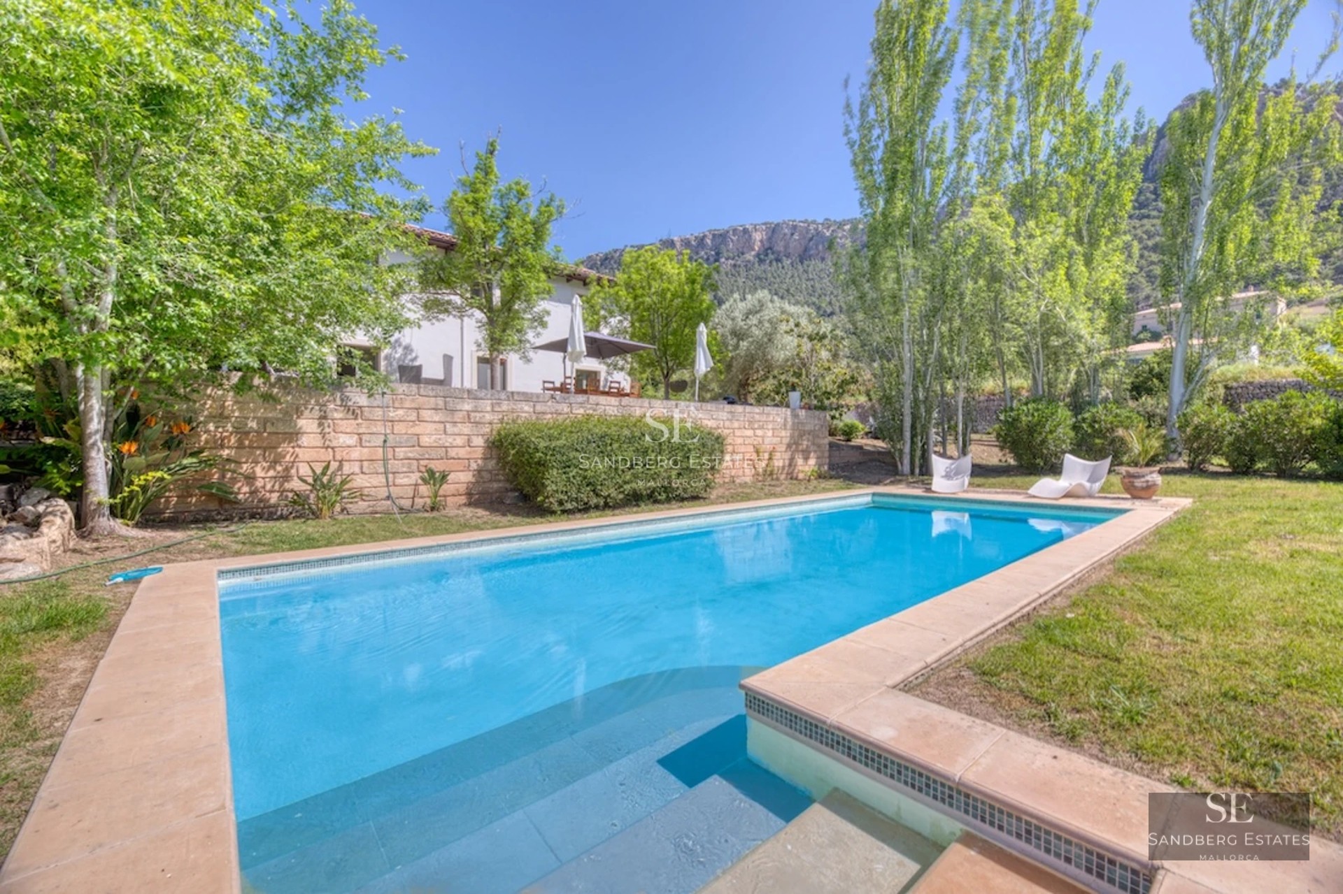 Image of a luxurious villa with a pool, surrounded by gardens and offering stunning views. Modern and elegant architecture.