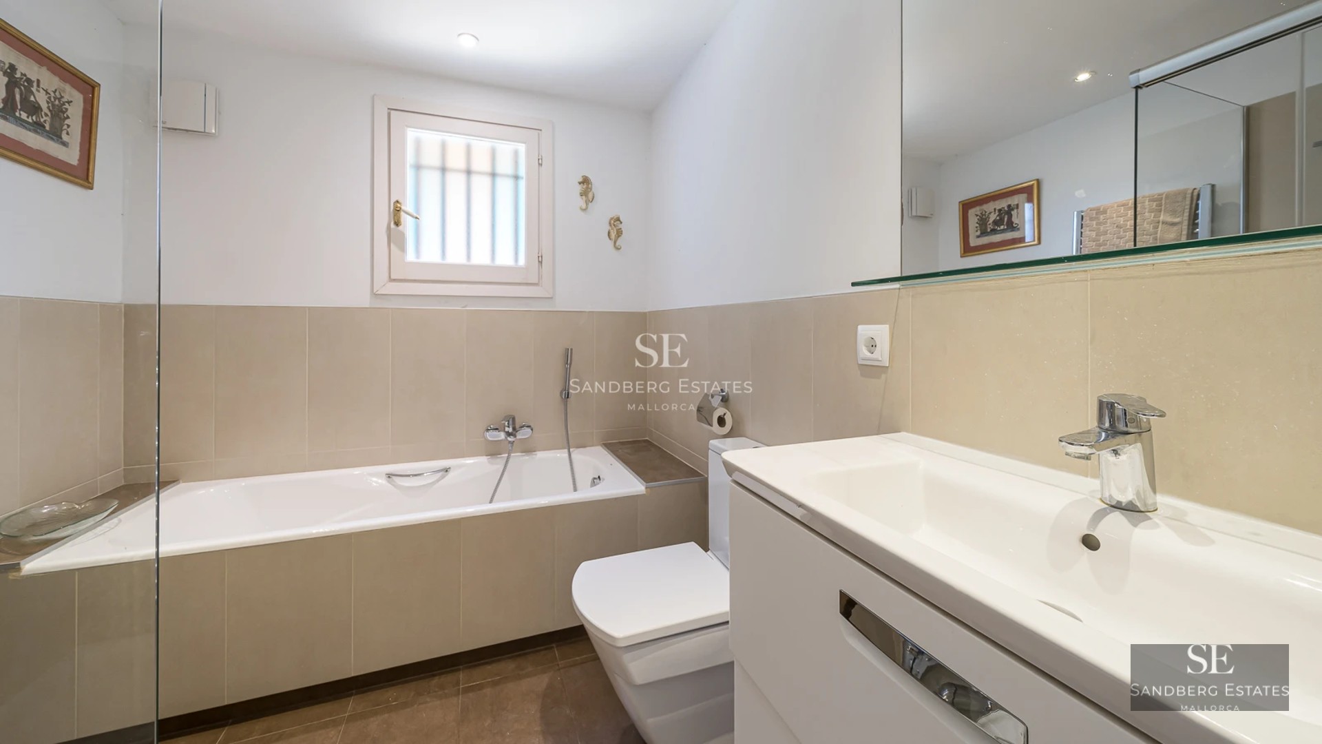 Spacious living room with large windows offering panoramic sea views. Modern, elegant design. Gray sectional sofa and light wood flooring.