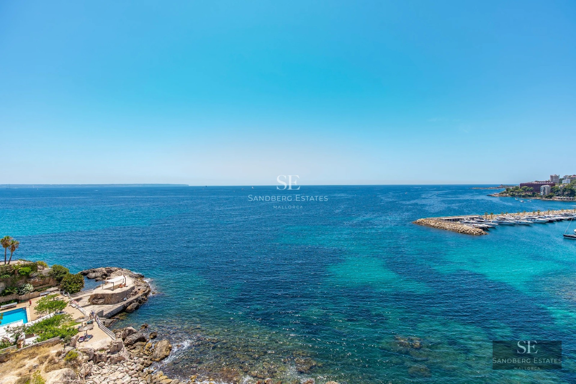 Bright interior with sea view. Large windows, light wood flooring, and minimalist decor. Elegance and comfort in a prime location.