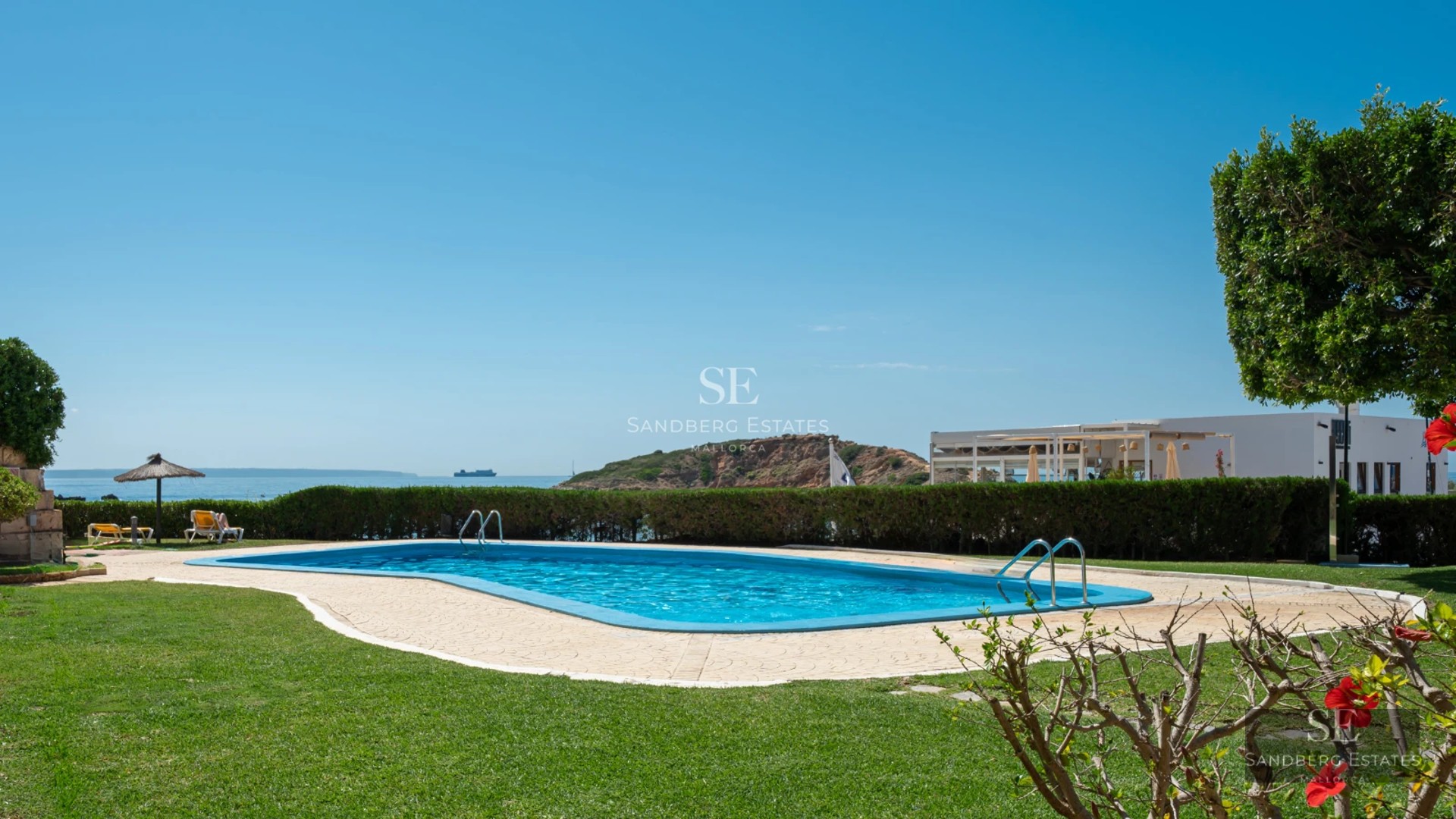 Image of an infinity pool overlooking the sea. Modern, minimalist architecture, wooden terrace and lush garden.