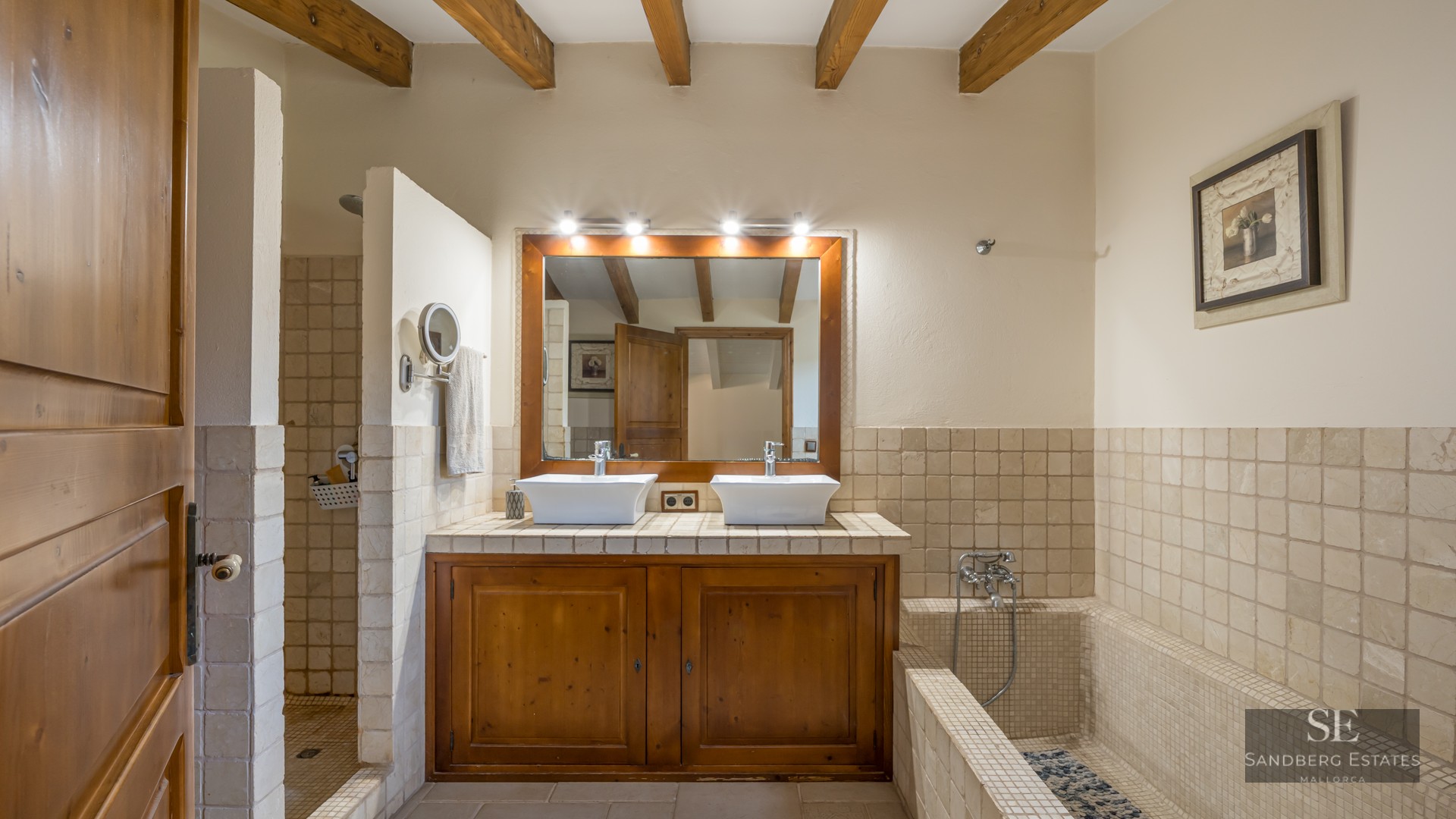 Master bathroom with double vessel sinks, wooden vanity, exposed ceiling beams, a walk-in shower, and a tiled bathtub.