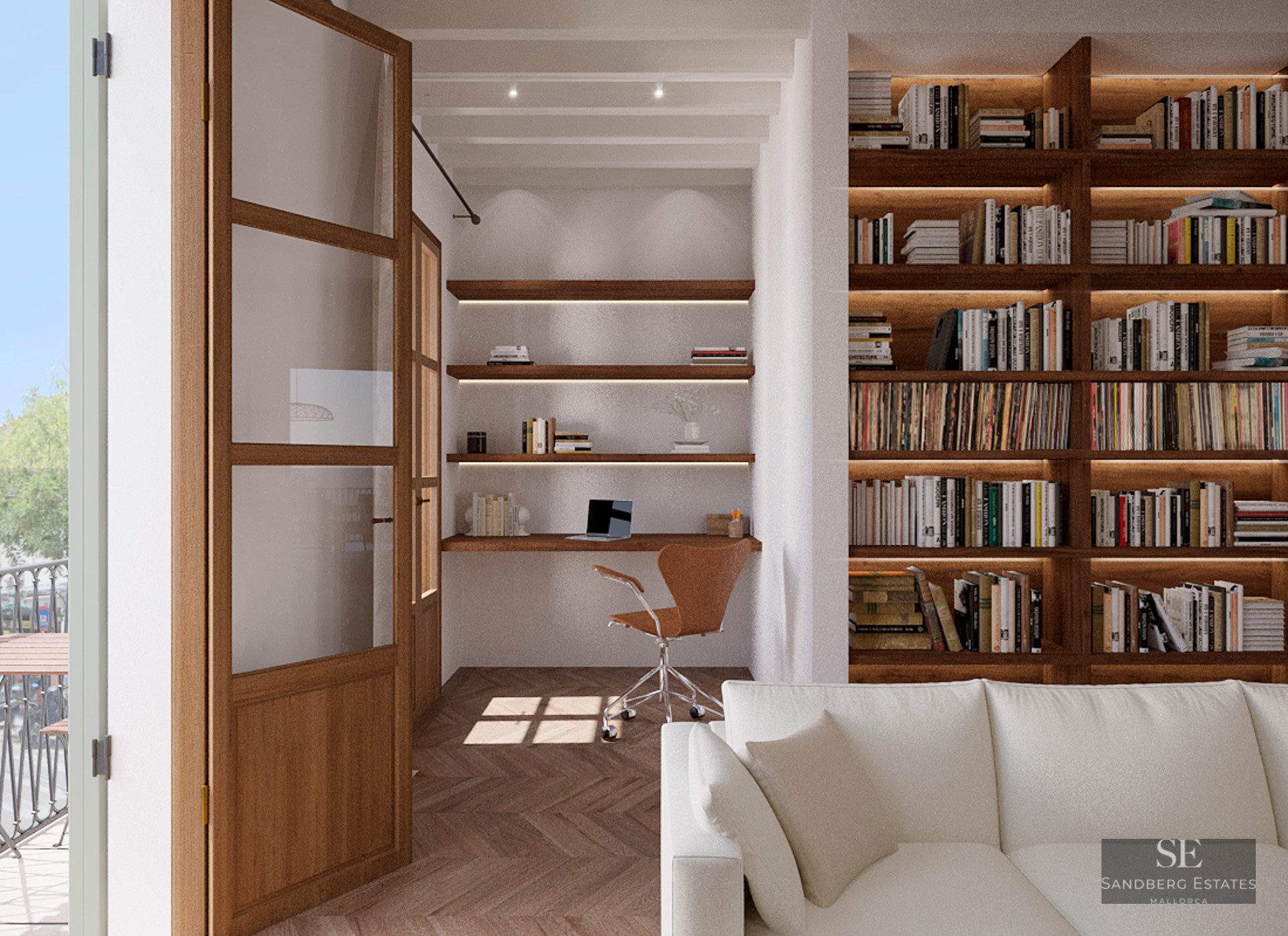 Modern home office nook featuring a wooden desk, floating shelves, and a large built-in bookshelf next to a white sofa.