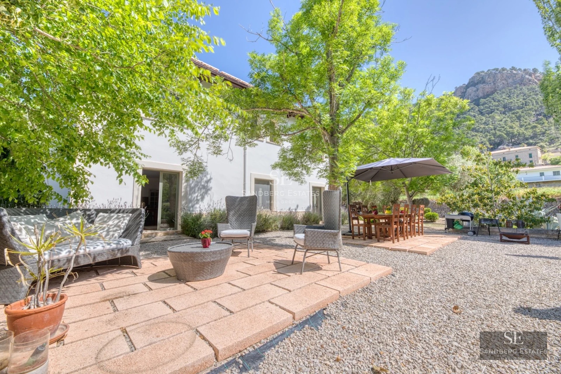 Image of a swimming pool with panoramic views, surrounded by lush greenery and a modern house with large glass windows.