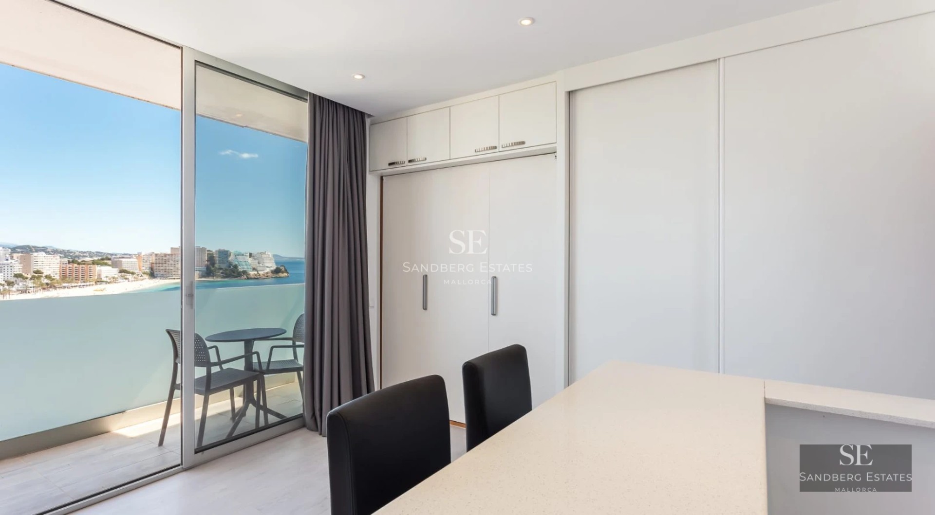 Spacious balcony with sea views, glass railing, modern furniture, and wooden floor. Minimalist and elegant design.