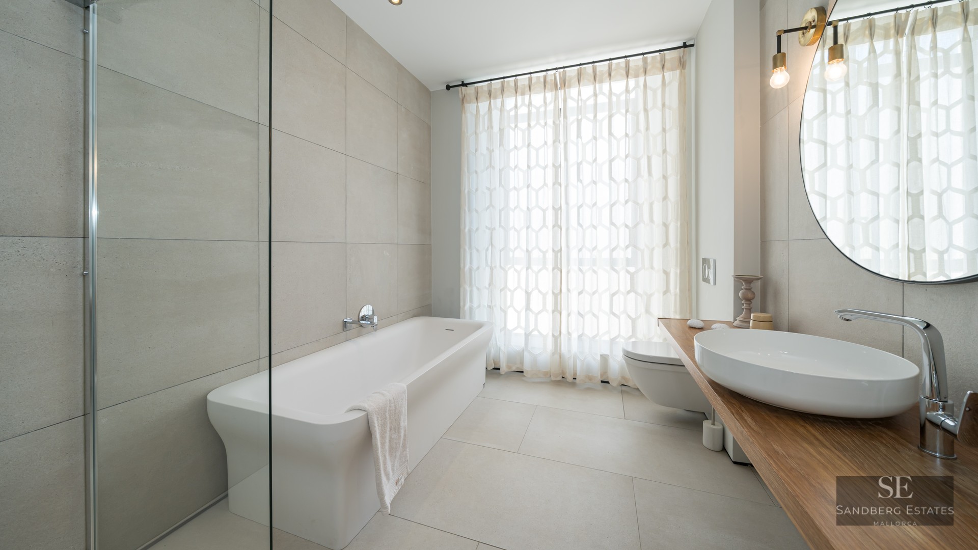 Large bathroom featuring a white bathtub, vessel sink on a wooden counter, and glass shower screen.