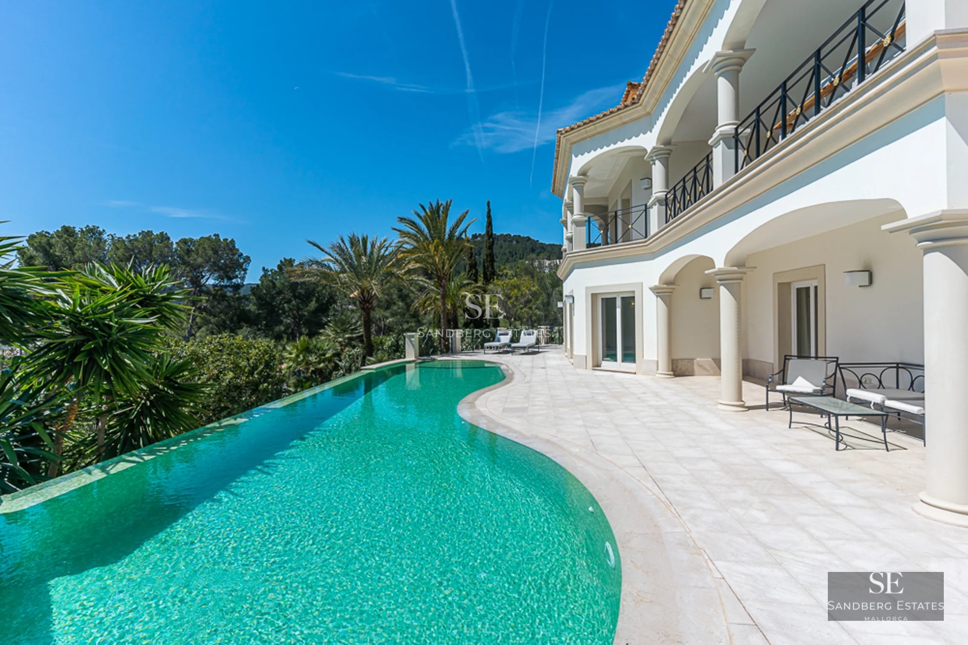 Spacious living room with floor-to-ceiling windows, designer sofas, modern fireplace and panoramic views. Natural and warm lighting.