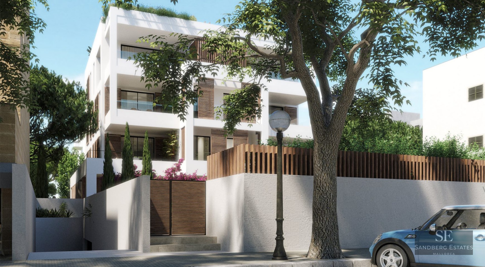 White multi-story modern building with wooden shutters and glass balconies behind a stone wall and street lamp.