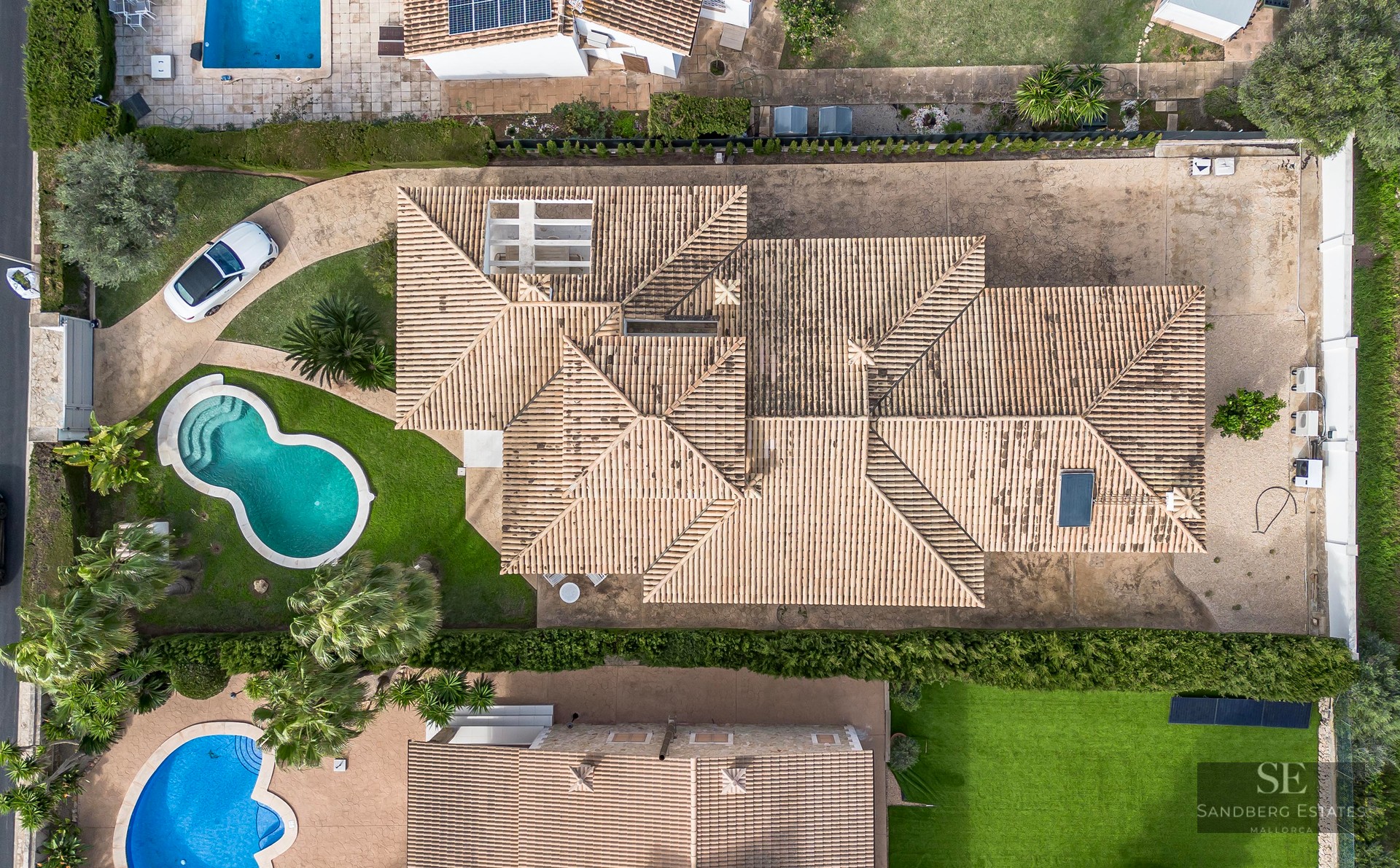 Top-down aerial view of a large villa featuring a terracotta tiled roof, private swimming pool, and landscaping.