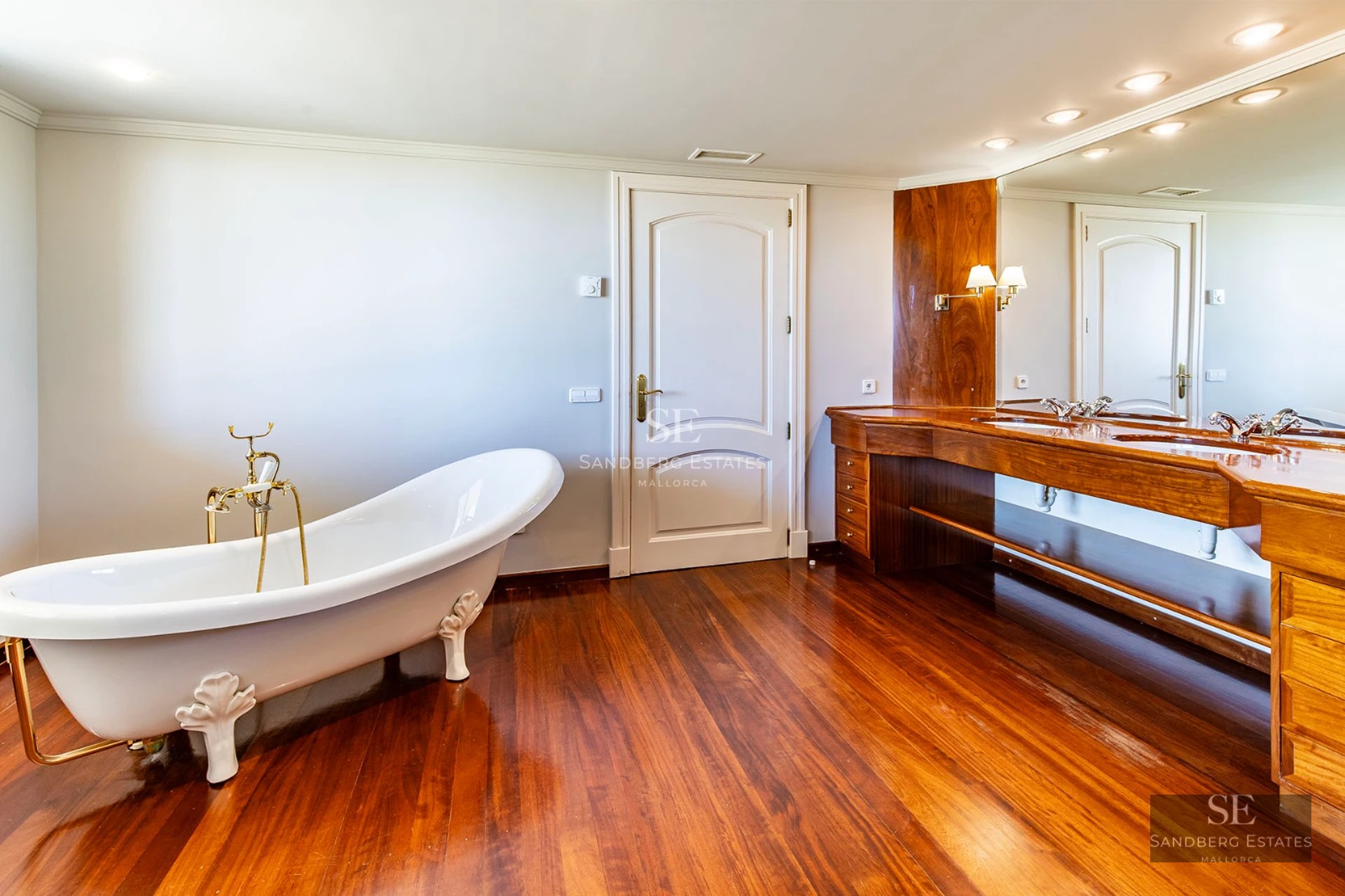 Spacious living room with windows, designer sofas, and balcony access with view. Natural lighting and wood floors.