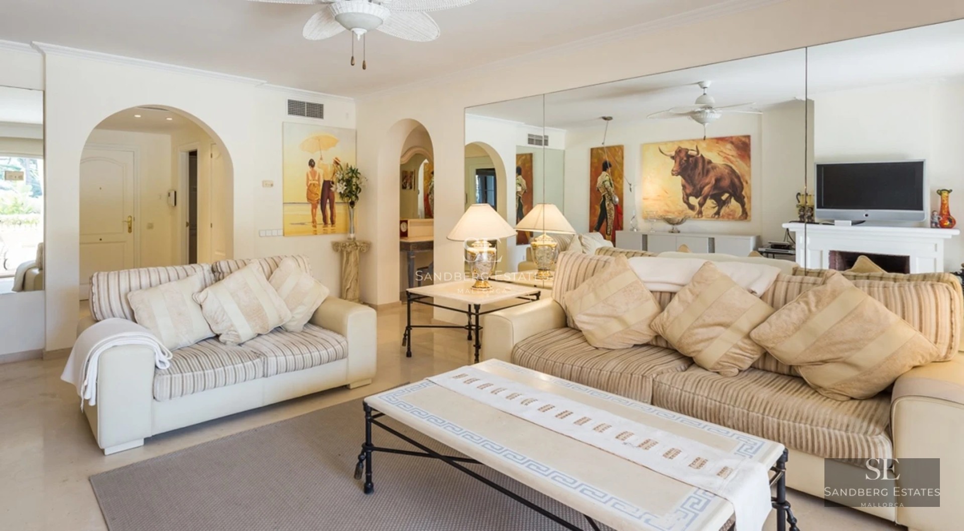 Spacious, bright living room with large windows, light wood flooring and modern furniture. Panoramic outdoor views.