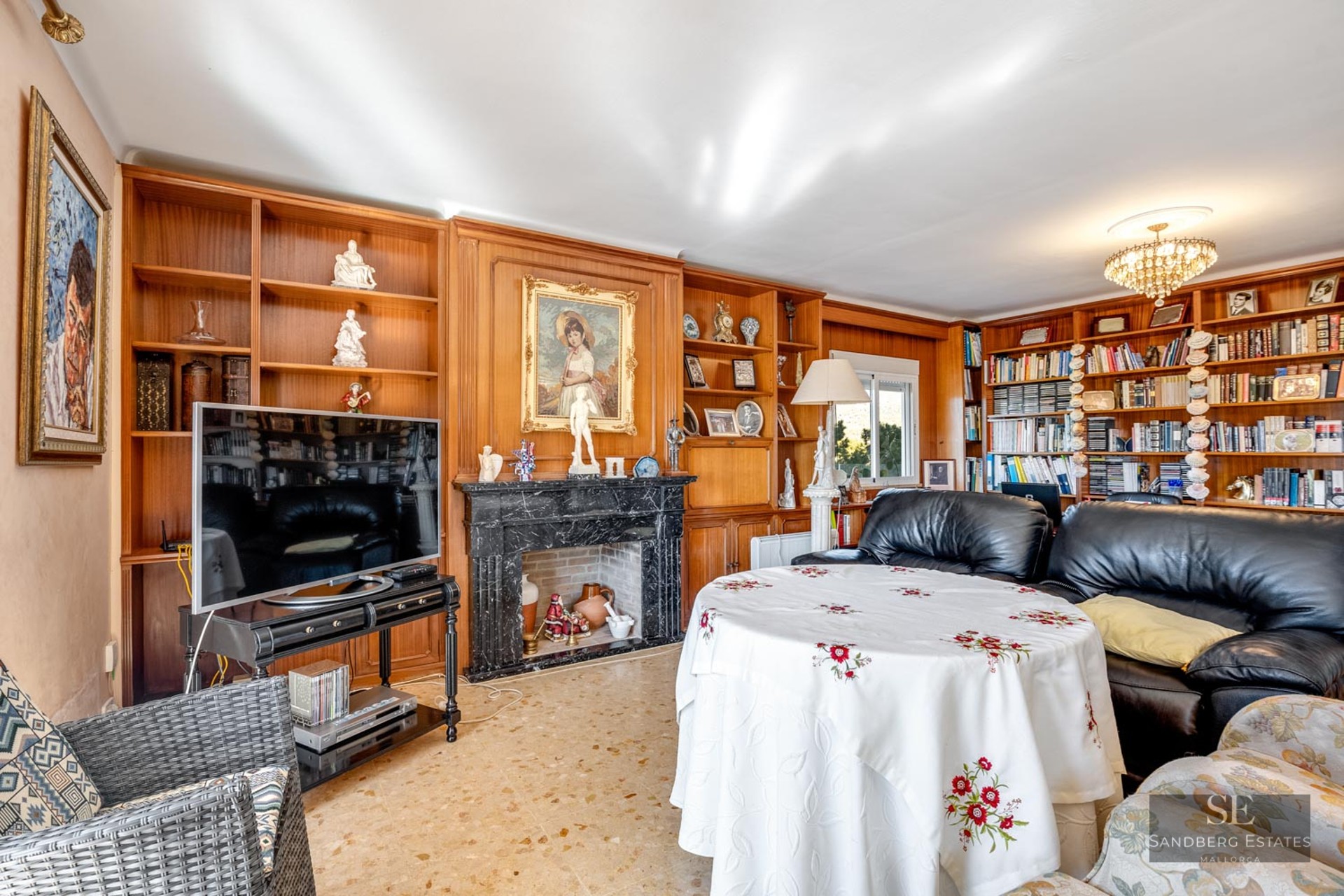 Traditional living room featuring a black marble fireplace, custom wood shelving, and black leather sofas.