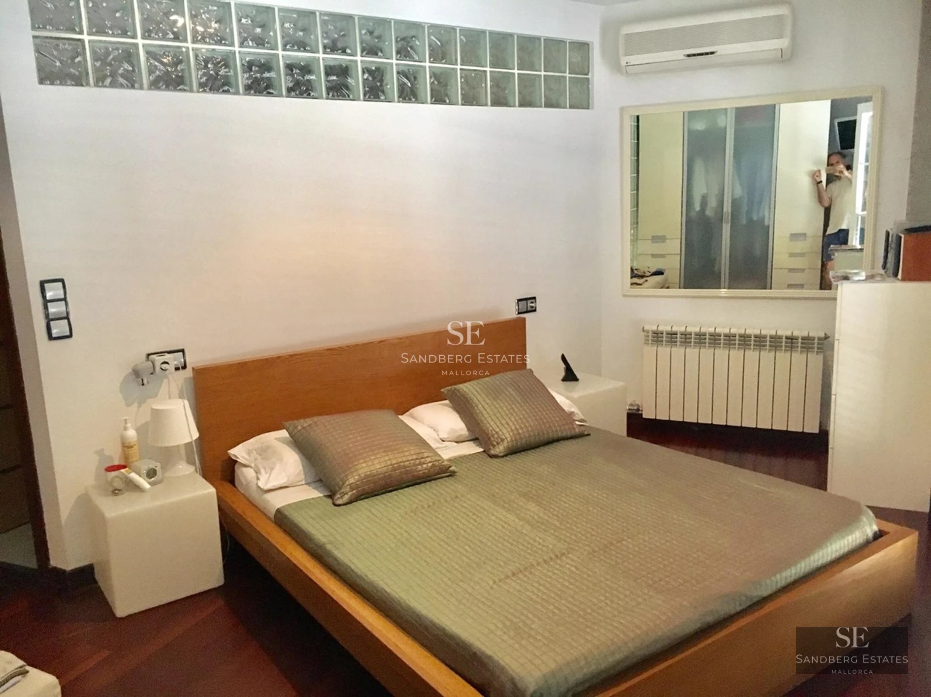 Spacious living room with picture windows, light wood floors, and minimalist design. Abundant natural light. Gray modular sofa.