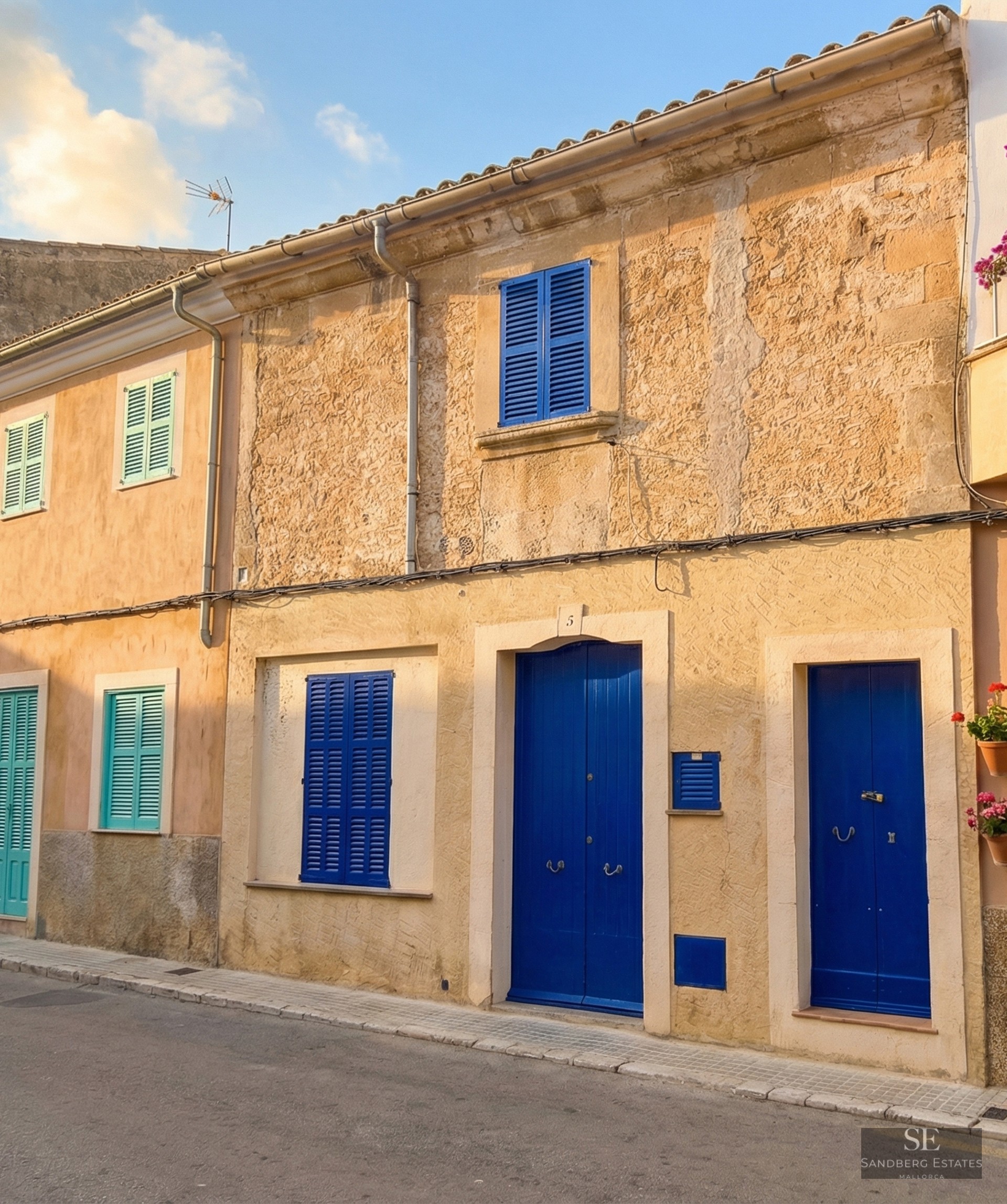 Ochre stone facade featuring vibrant blue wooden doors and shutters on a quiet street.