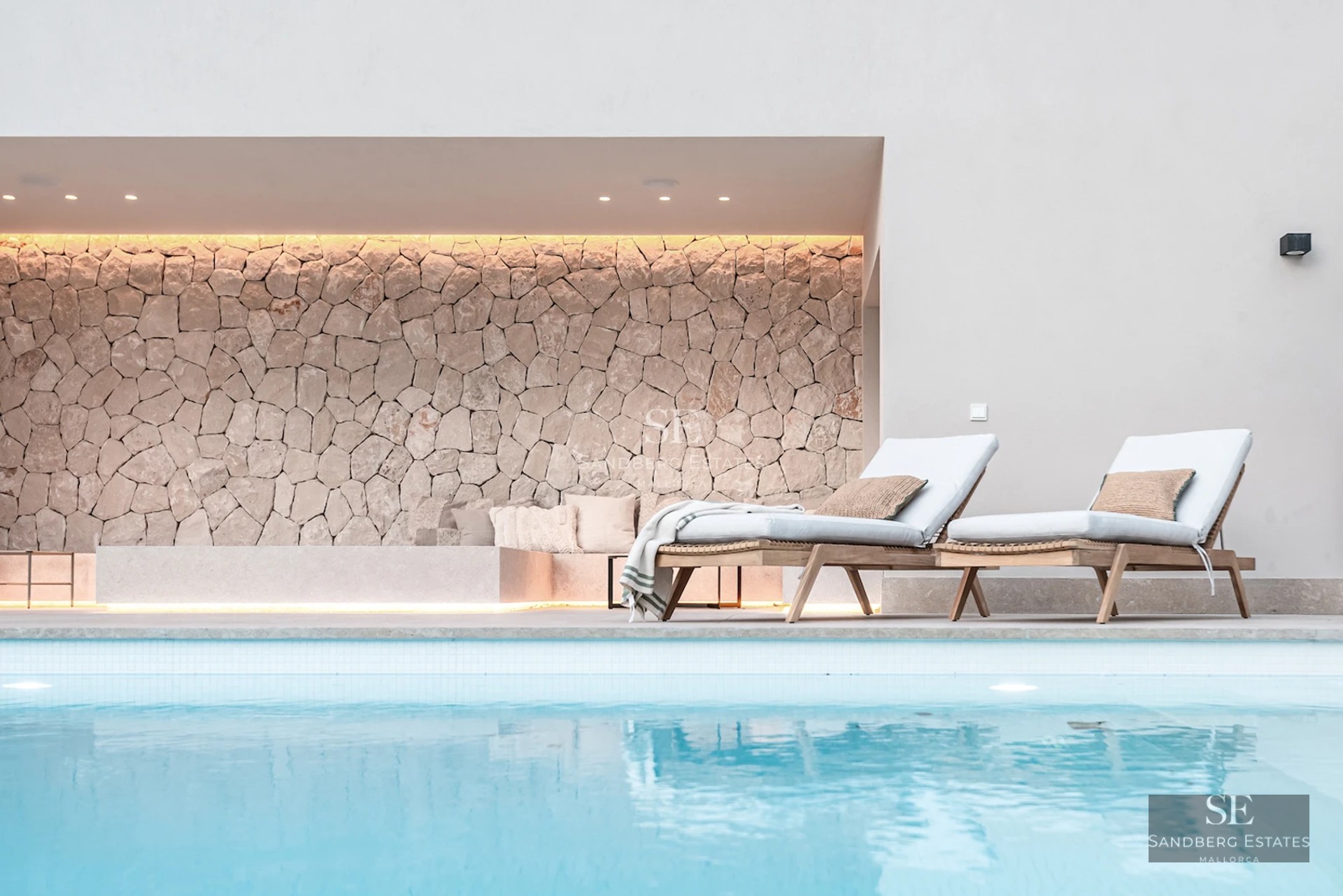 Spacious balcony with glass railing, wooden floor, panoramic view of the city skyline and blue sky at sunset.