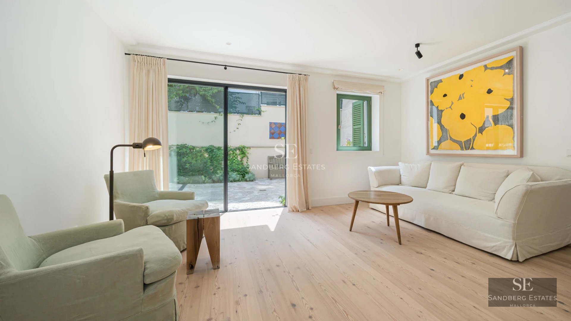 Spacious balcony with glass railings, panoramic sea views, and modern furniture. Wooden flooring and vegetation.