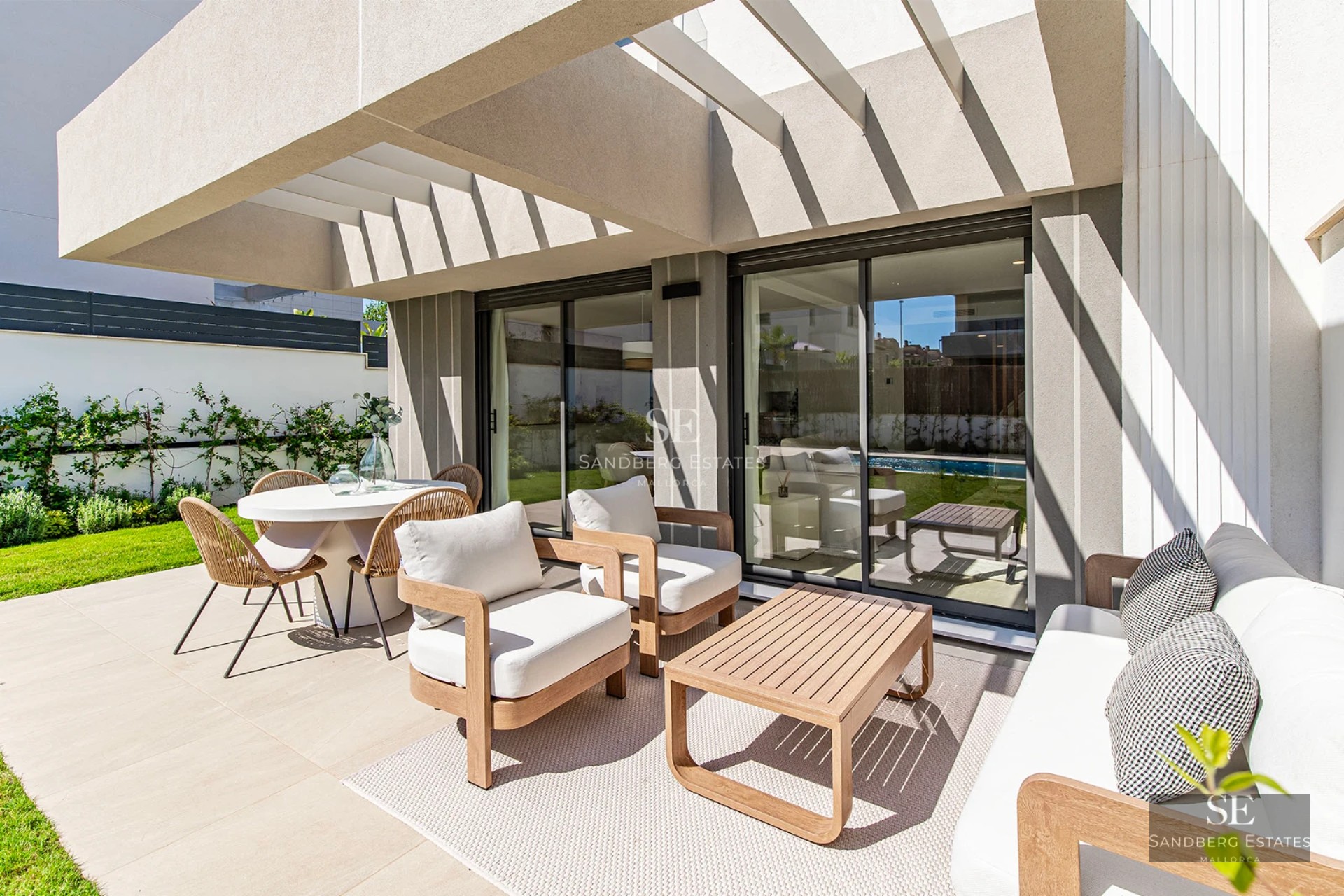 View of modern villa with infinity pool, lush garden, and minimalist architectural design. Large windows and covered terrace.