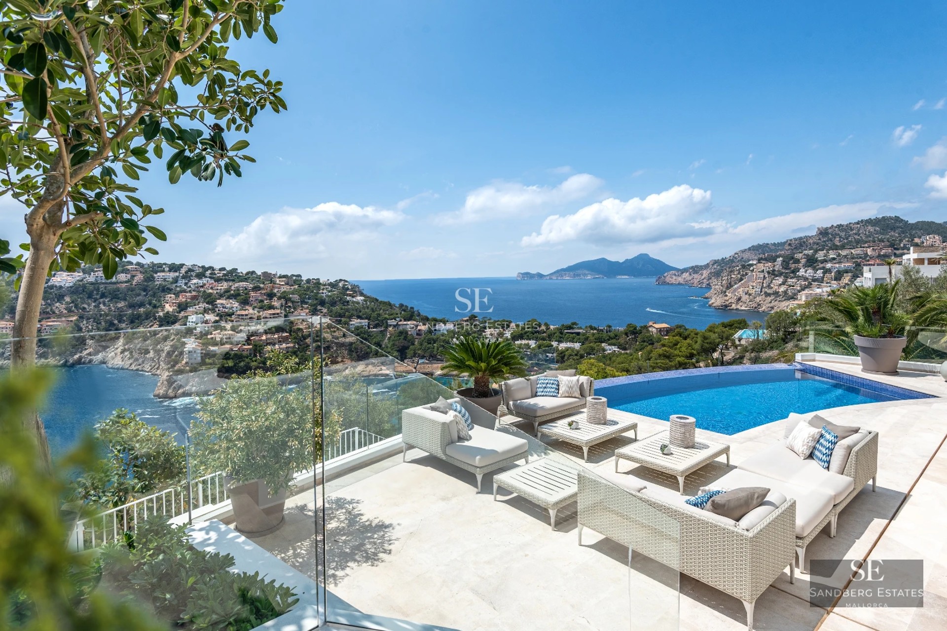 Expansive terrace with infinity pool. Panoramic views, modern furniture. Loungers, parasols, and lush vegetation.