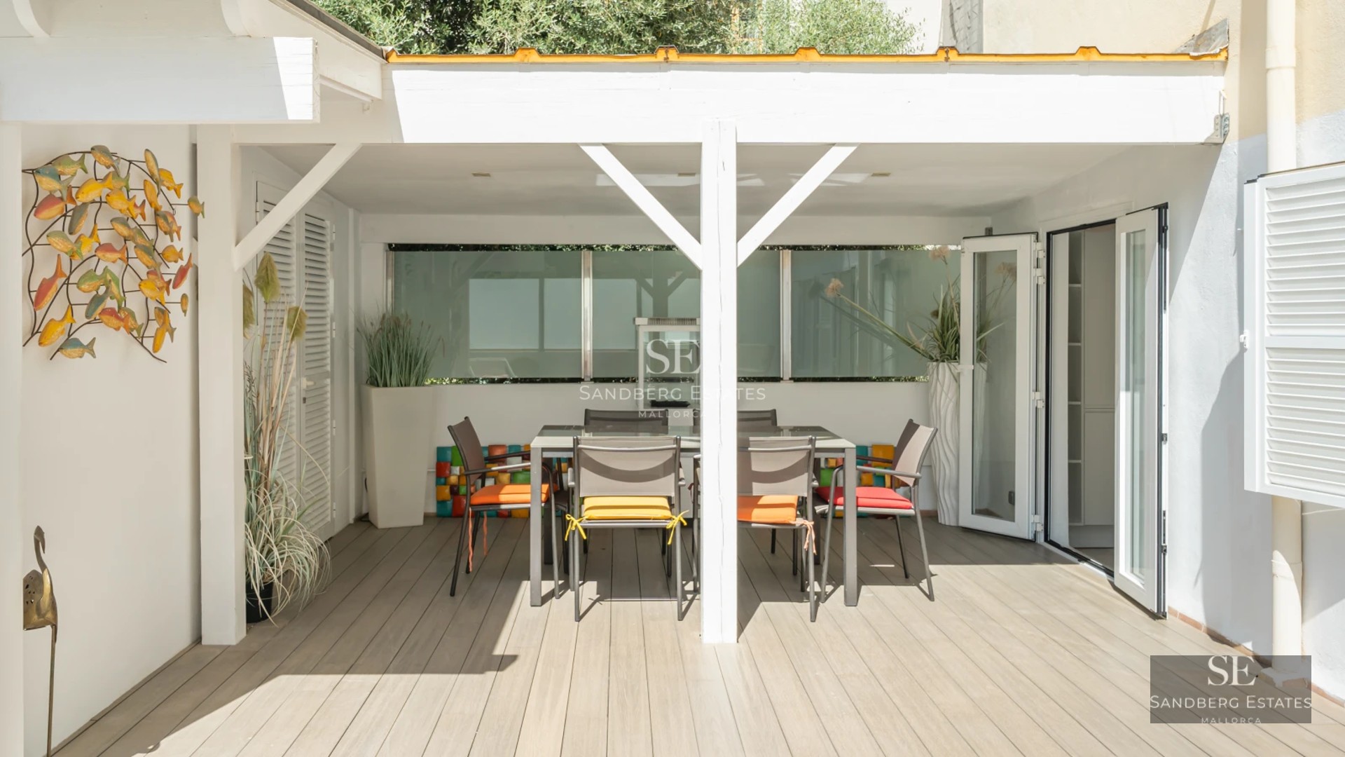 Large swimming pool lined with sun loungers, with a modern house with minimalist design in the background and lush vegetation.