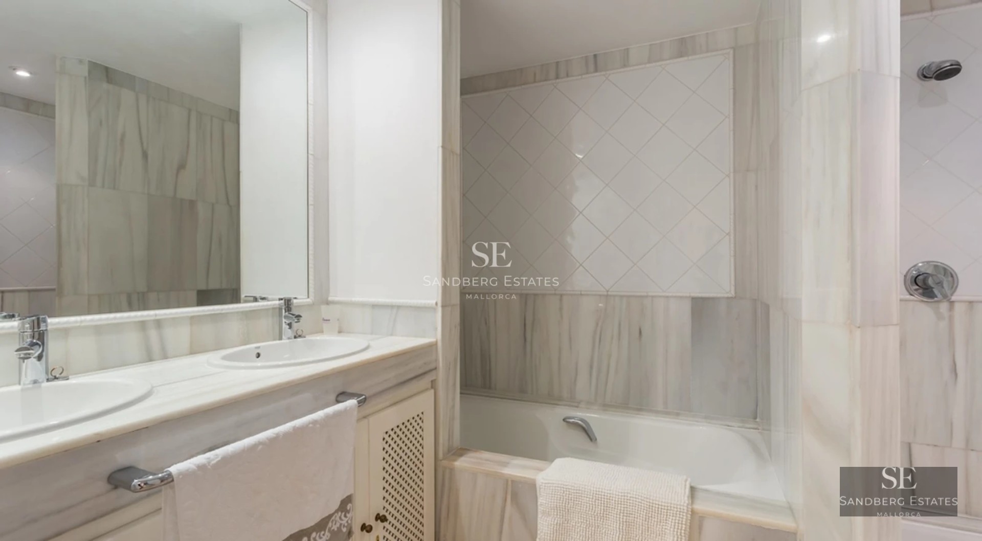 View of a luxurious pool with sun loungers, lush greenery, and a modern house with large windows in the background.