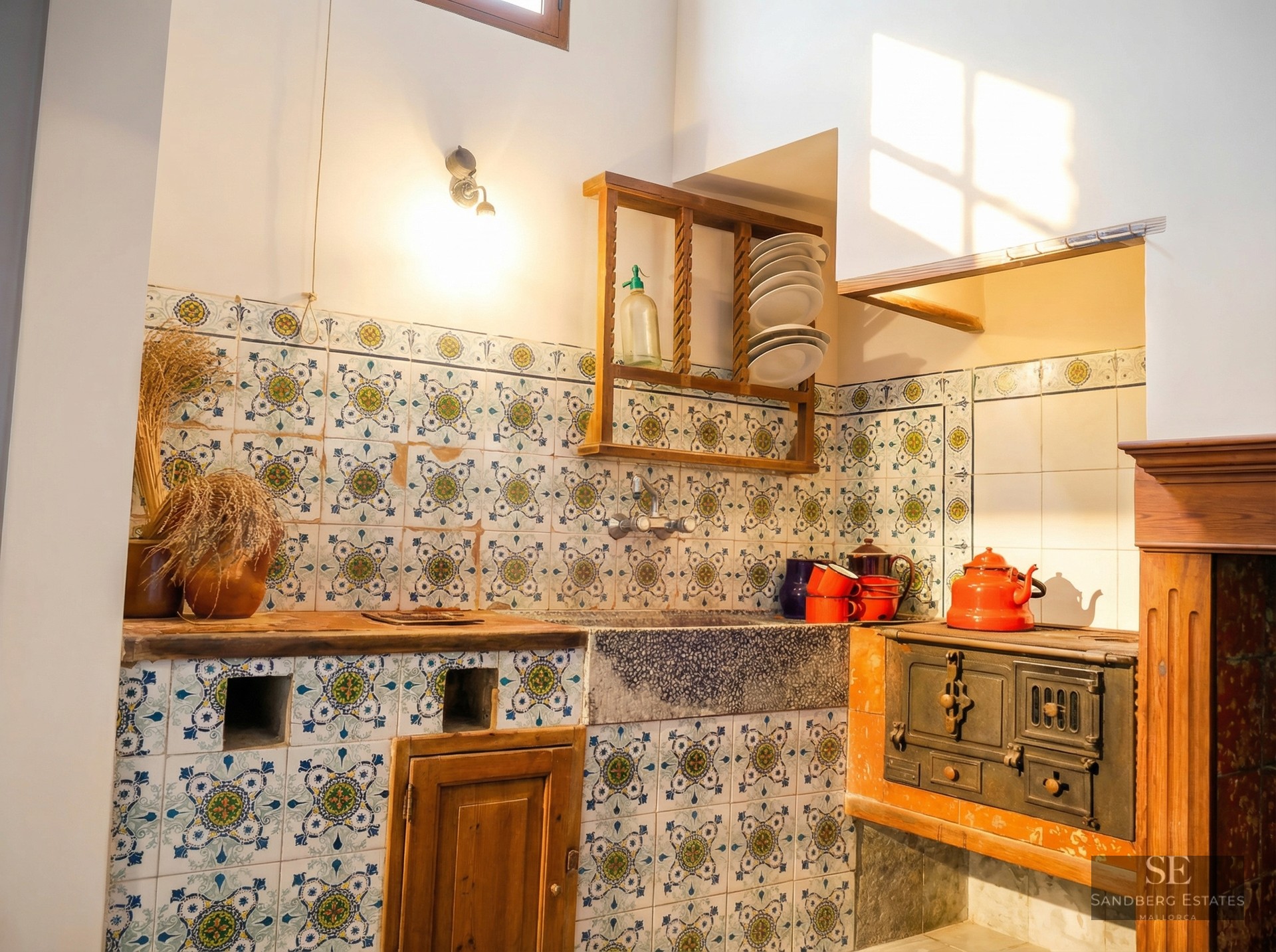 Rustic kitchen featuring hand-painted patterned tiles, a stone sink, and a vintage cast iron wood-burning stove.