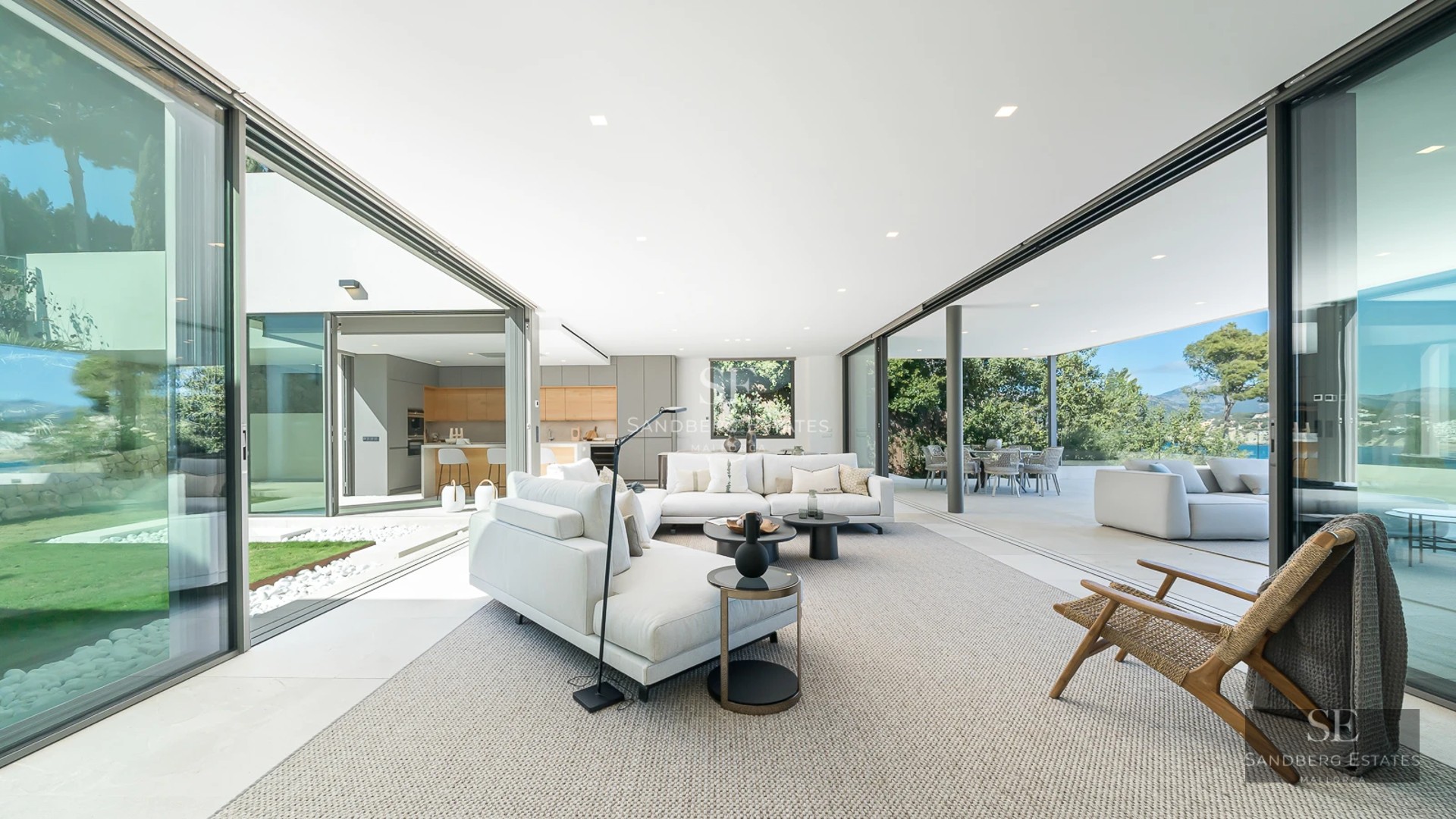 Large infinity pool, surrounded by lush vegetation and a modern house with large windows. Panoramic view of the horizon.