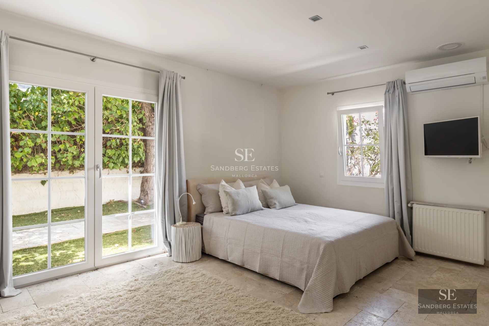 Spacious living room with floor-to-ceiling windows, light wood flooring, modern fireplace and minimalist furniture. Panoramic sea views. Bright and elegant.