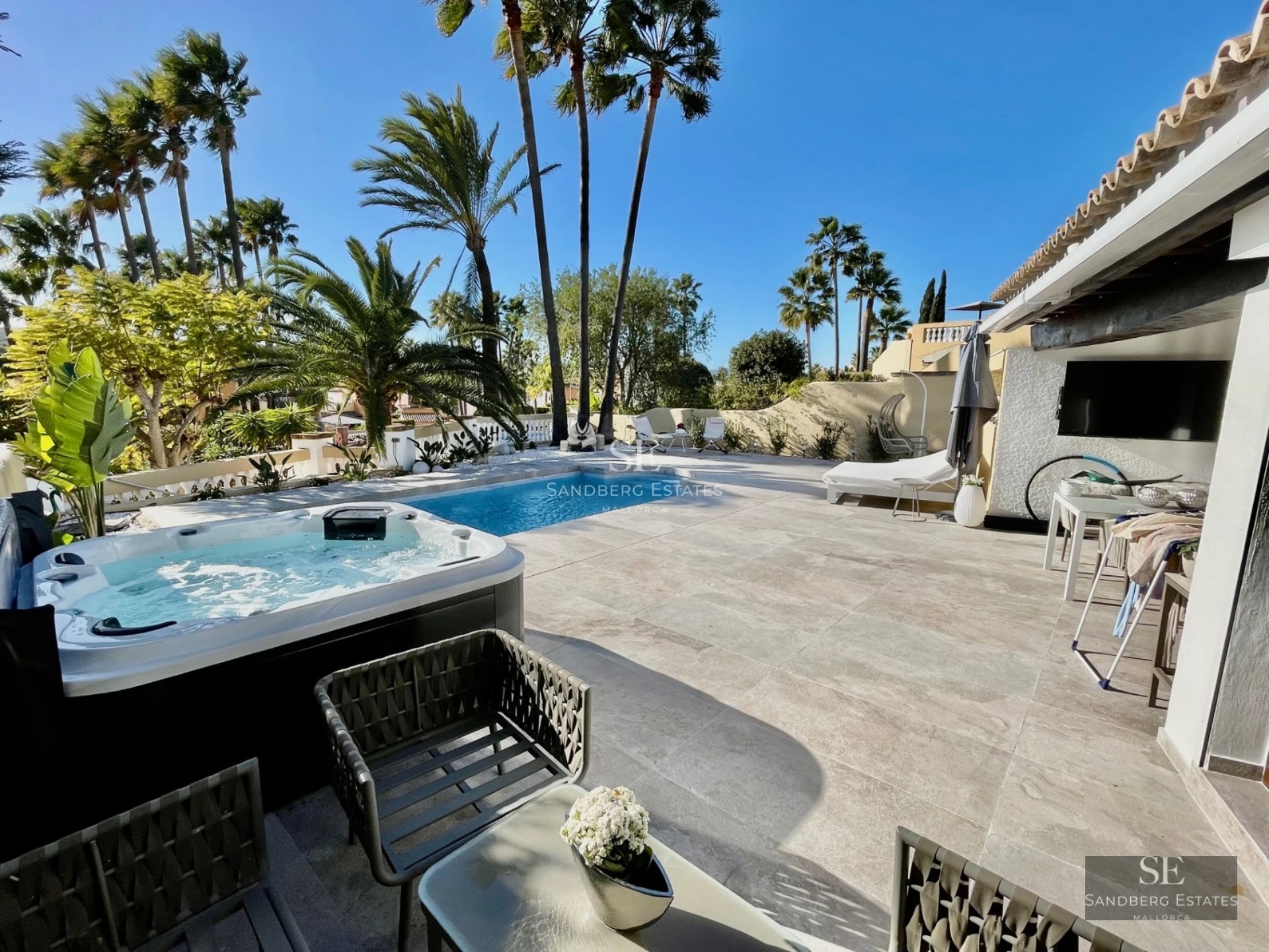 Aerial view of a luxurious villa with infinity pool, wooden terrace, and lush garden. Modern and minimalist design.