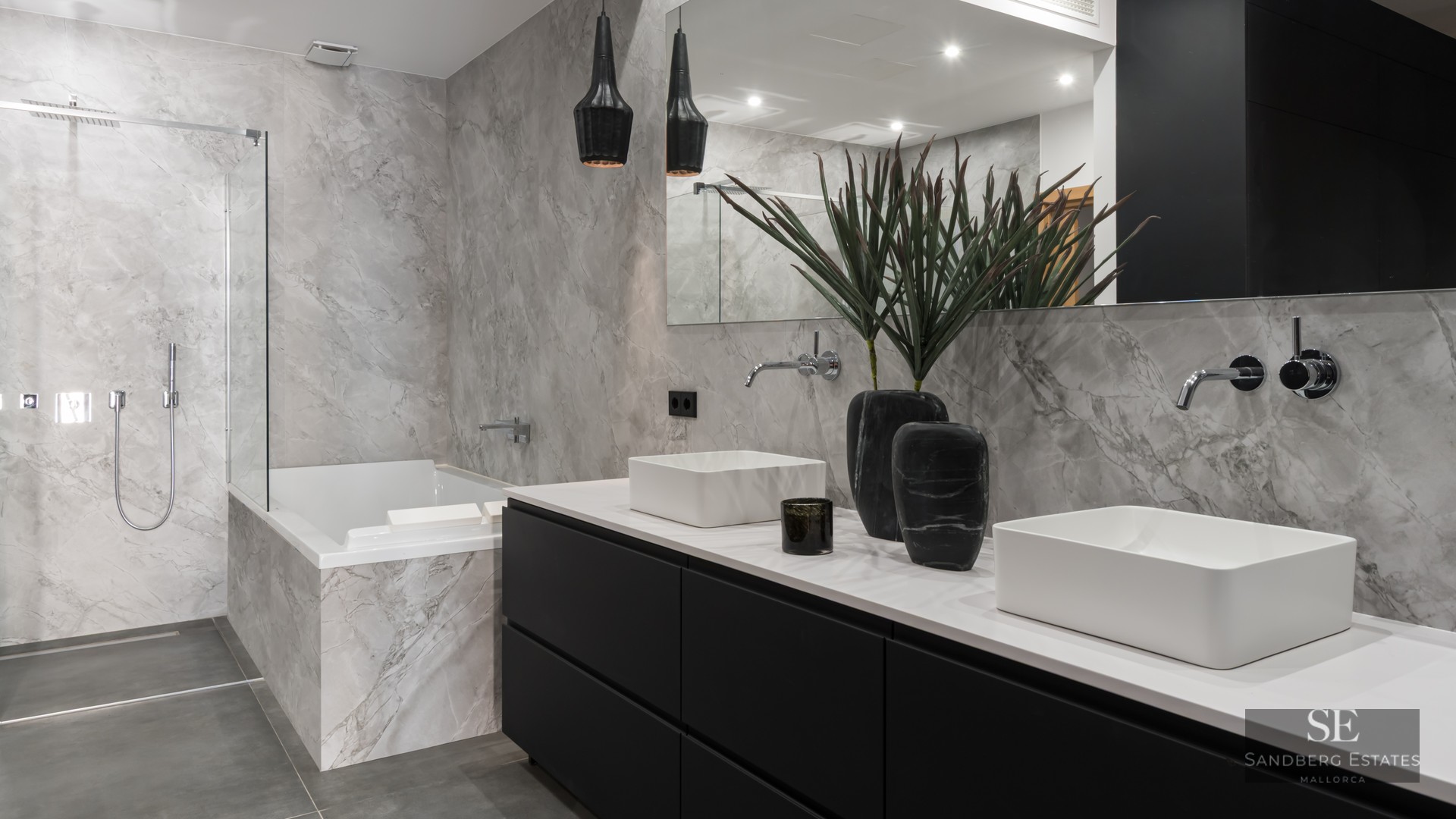 Luxury bathroom with double white sinks, black vanity, marble-tiled bathtub, and a glass-enclosed walk-in shower.