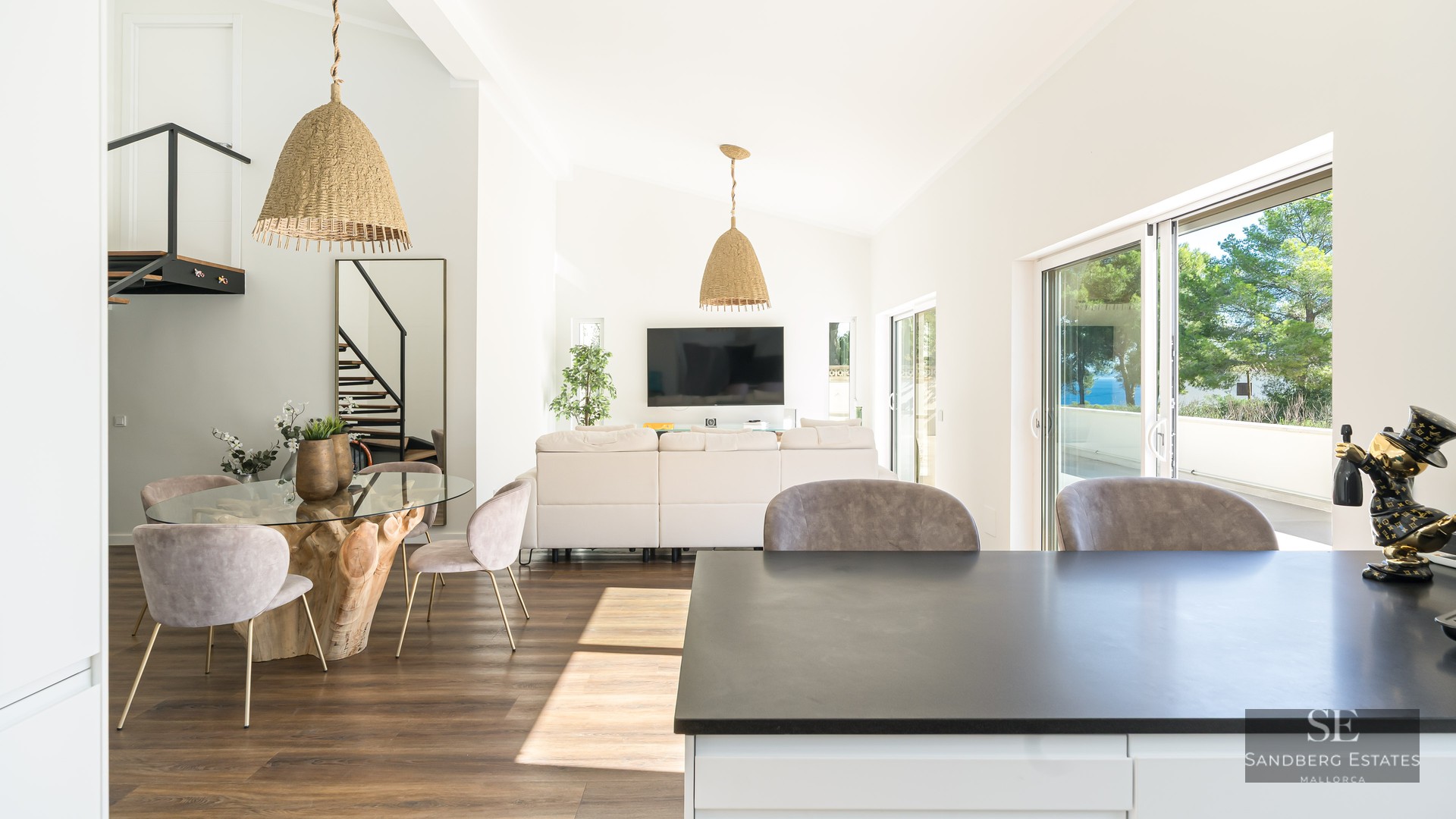 Grand salon à aire ouverte avec canapés blancs, table à manger avec base en racine et grandes baies vitrées.