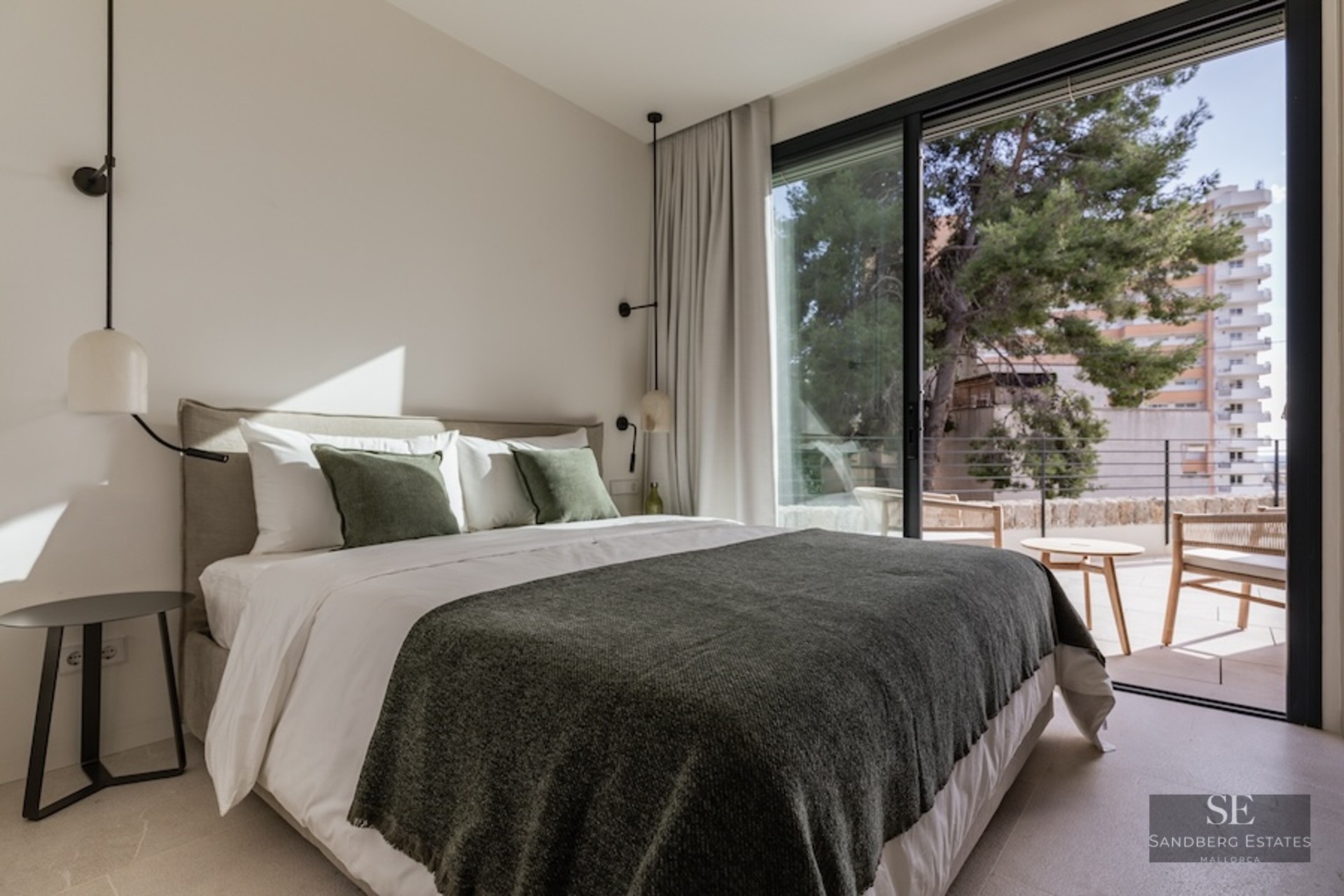 Bright bedroom featuring a double bed with green accents and large glass sliding doors opening to a terrace.