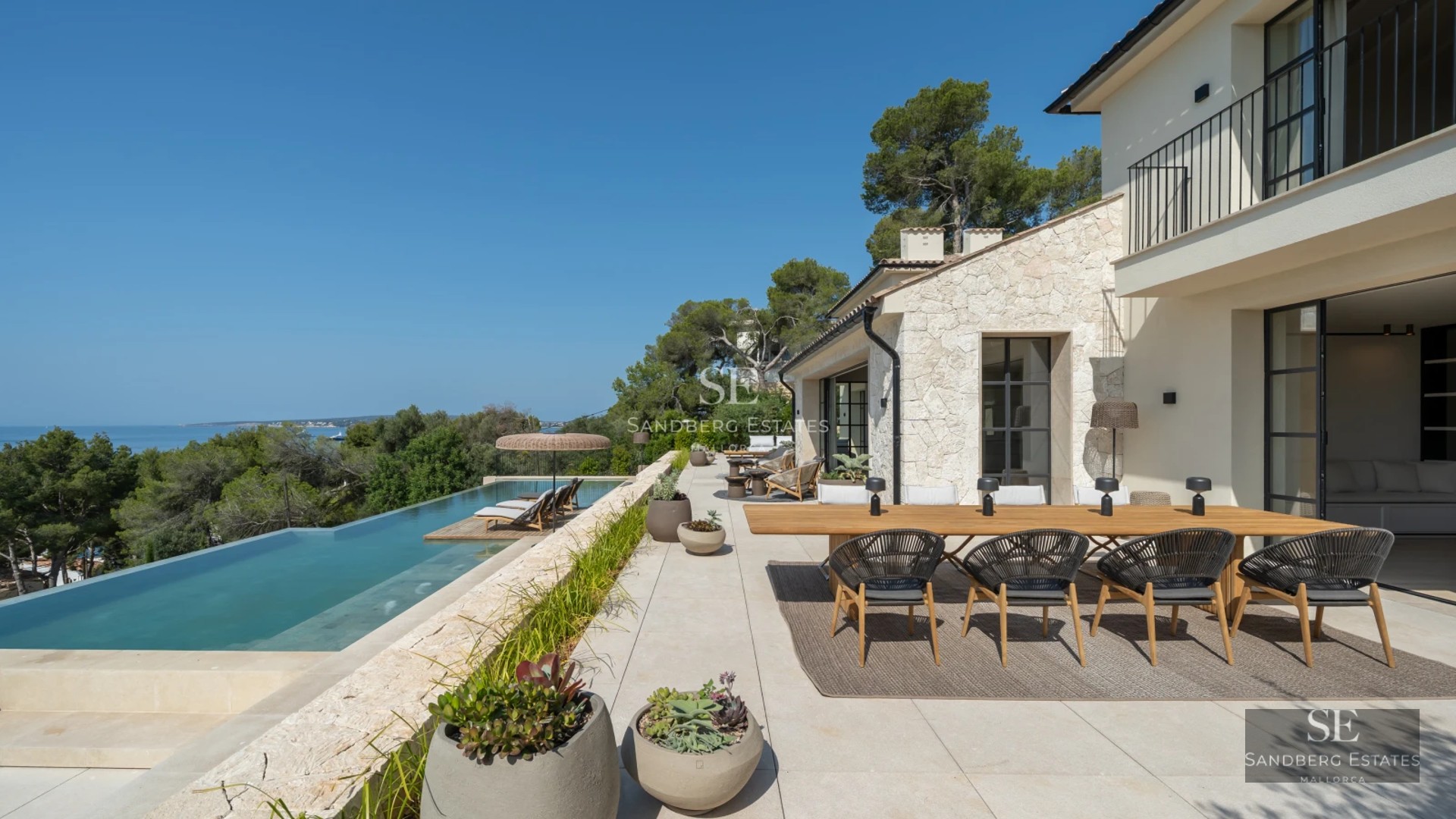 Spacious balcony with panoramic sea views. Modern design, glass railing, wooden floor. Elegant outdoor furniture.