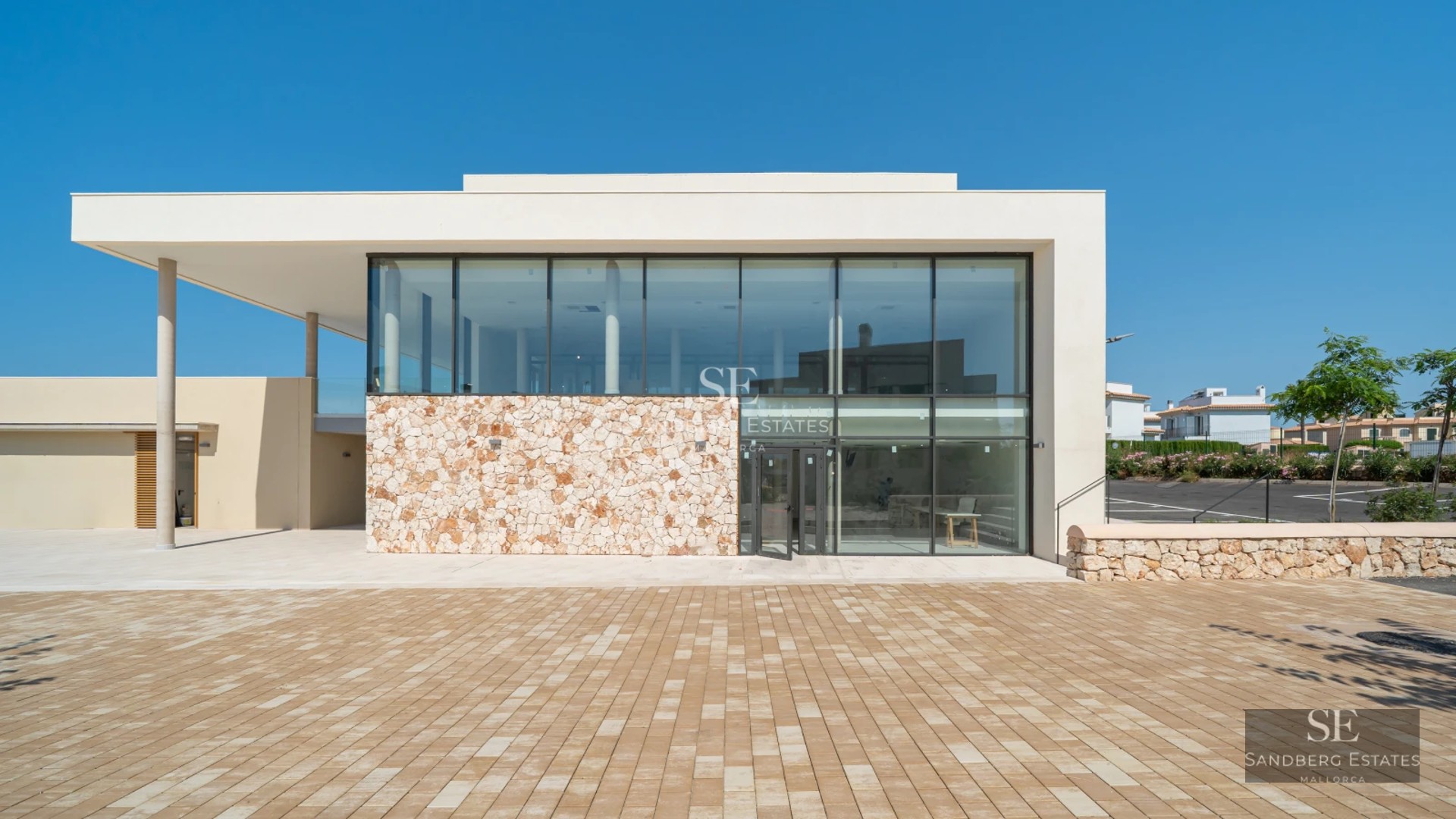 Spacious living room with large windows, sea views, and modern decor. Light wood floors and minimalist furniture.